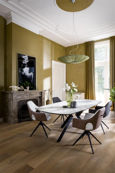 Stilvolles Esszimmer mit Marmorplatte und Kaminakzent. Elegantes Esszimmer mit Marmor-Esstisch, gepolsterten Stühlen, Kamin und großem Fenster mit grünen Vorhängen.