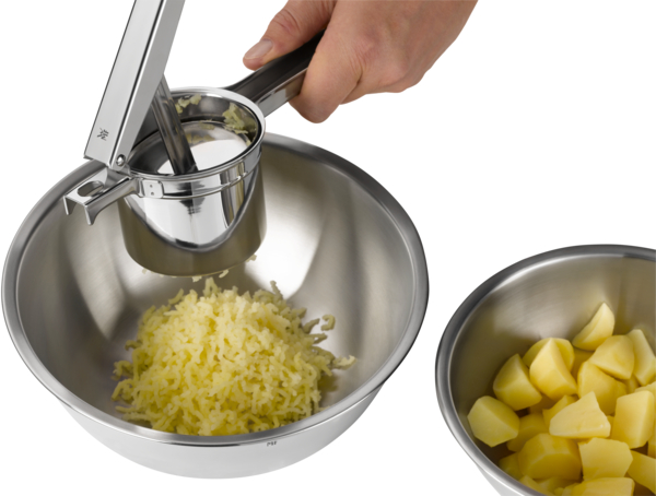 Kartoffelpresse in Benutzung Hand drückt Hebel geriebene Kartoffeln fallen in Schüssel  daneben Schüssel mit Würfeln