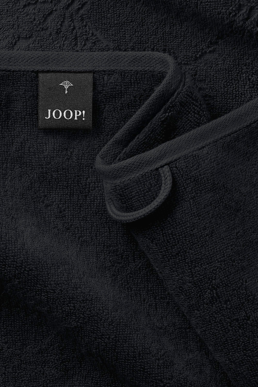 Nahaufnahme obere Ecke schwarzes JOOP Duschtuch feine Struktur gewebter Aufhänger Markenetikett