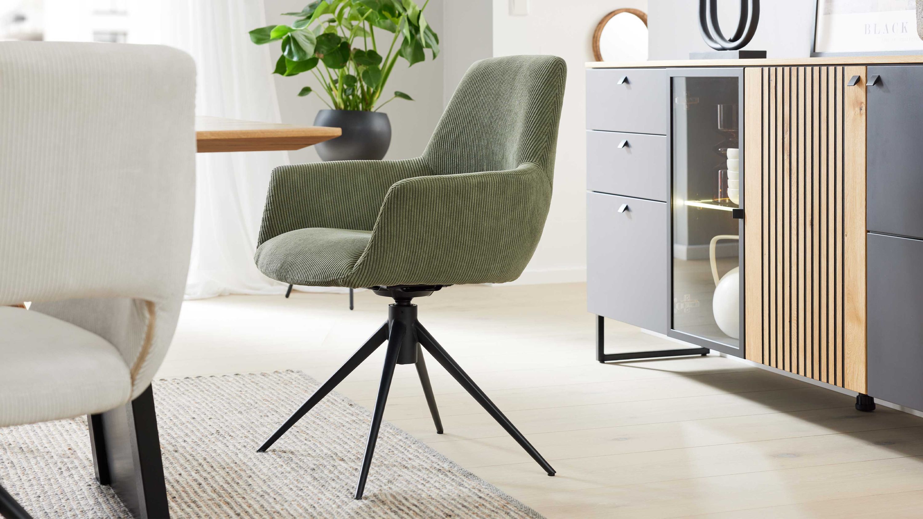 Armlehnstuhl mit Drehfunktion in waldgrünem Cordstoff und schwarzem Metallgestell in modernem Esszimmer