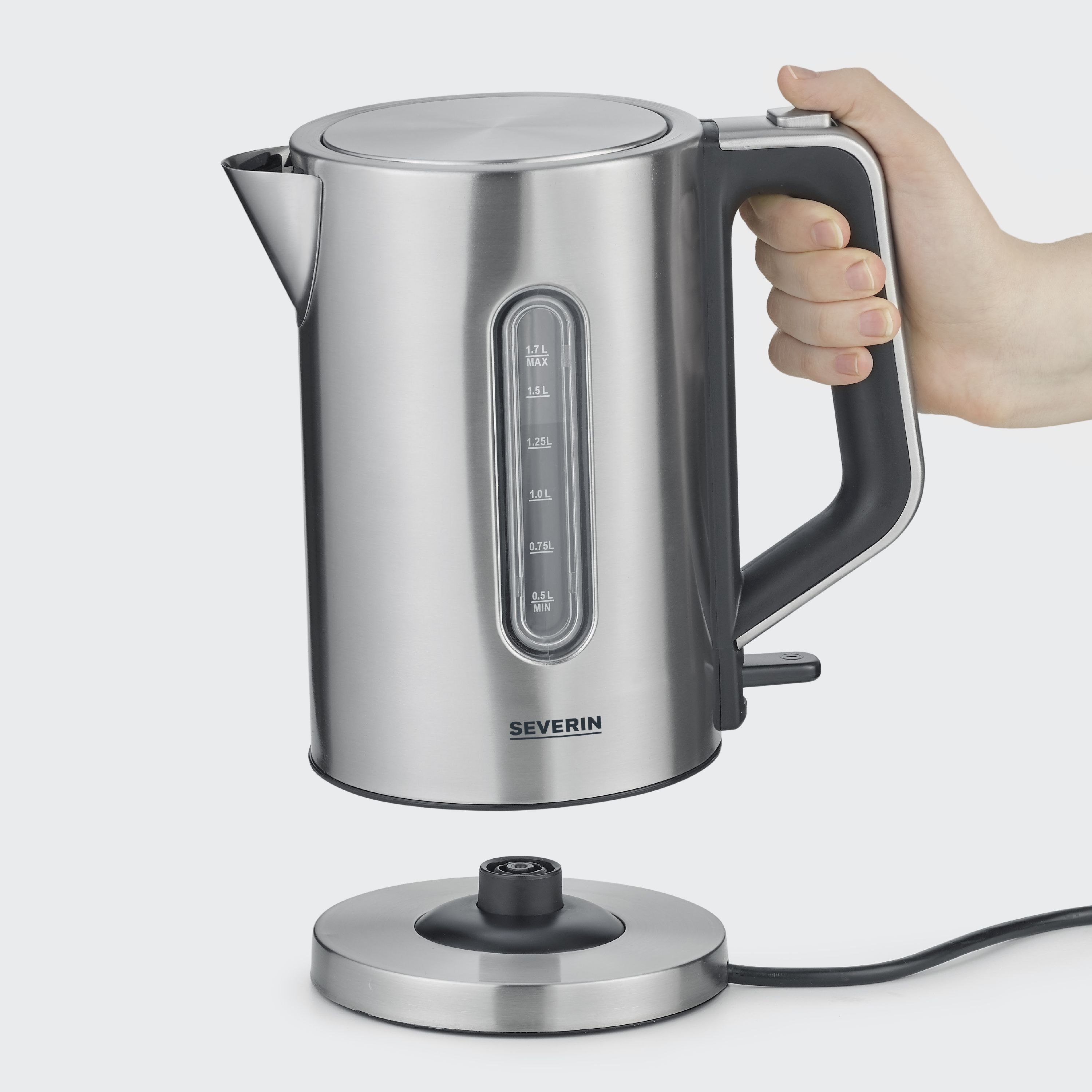 Seitlich fotografierter Wasserkocher in Silber-Schwarz Der Wasserkocher wird von einer Hand über der Basis gehalten