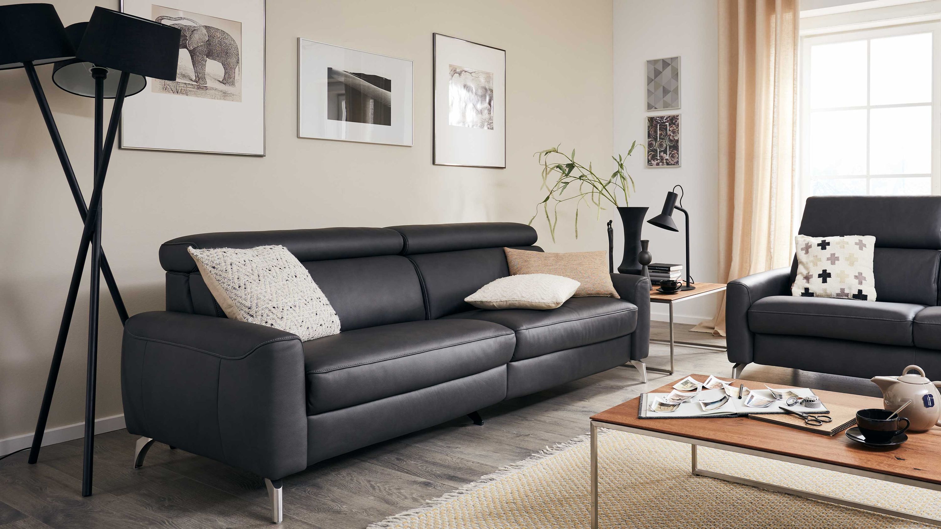 Dreisitziges Sofa in dunklem Leder mit verstellbaren Kopfstützen und Metallfüßen in einem hellen Wohnzimmer