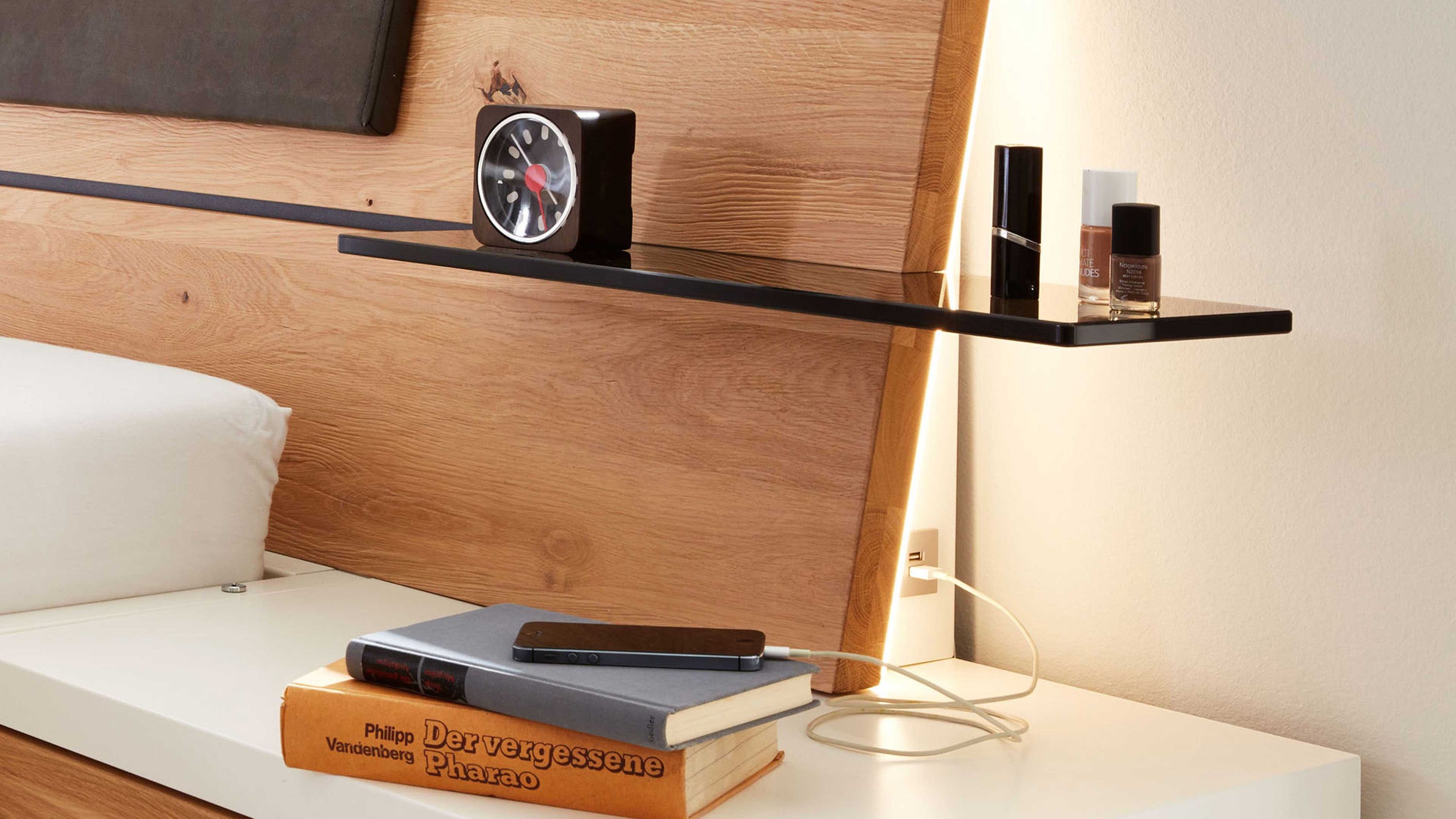 Zweiteiliges Glasboden-Set in dunklem Grau an Holzbettrückwand mit Uhr Kosmetik und Büchern