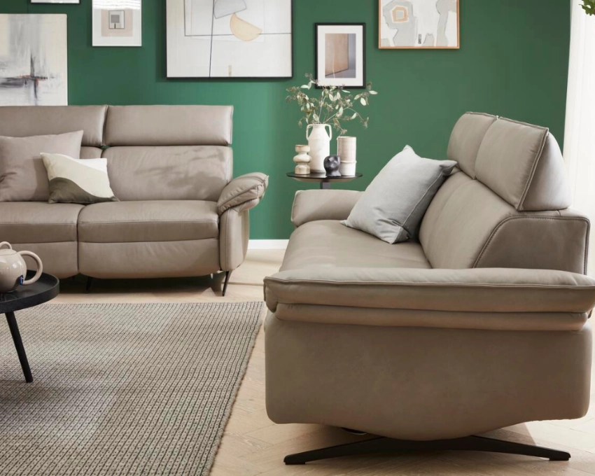 Zweisitzer von Himolla mit Relaxfunktion Beiges Relaxsofa in elegantem Wohnzimmer mit grüner Akzentwand und Deko