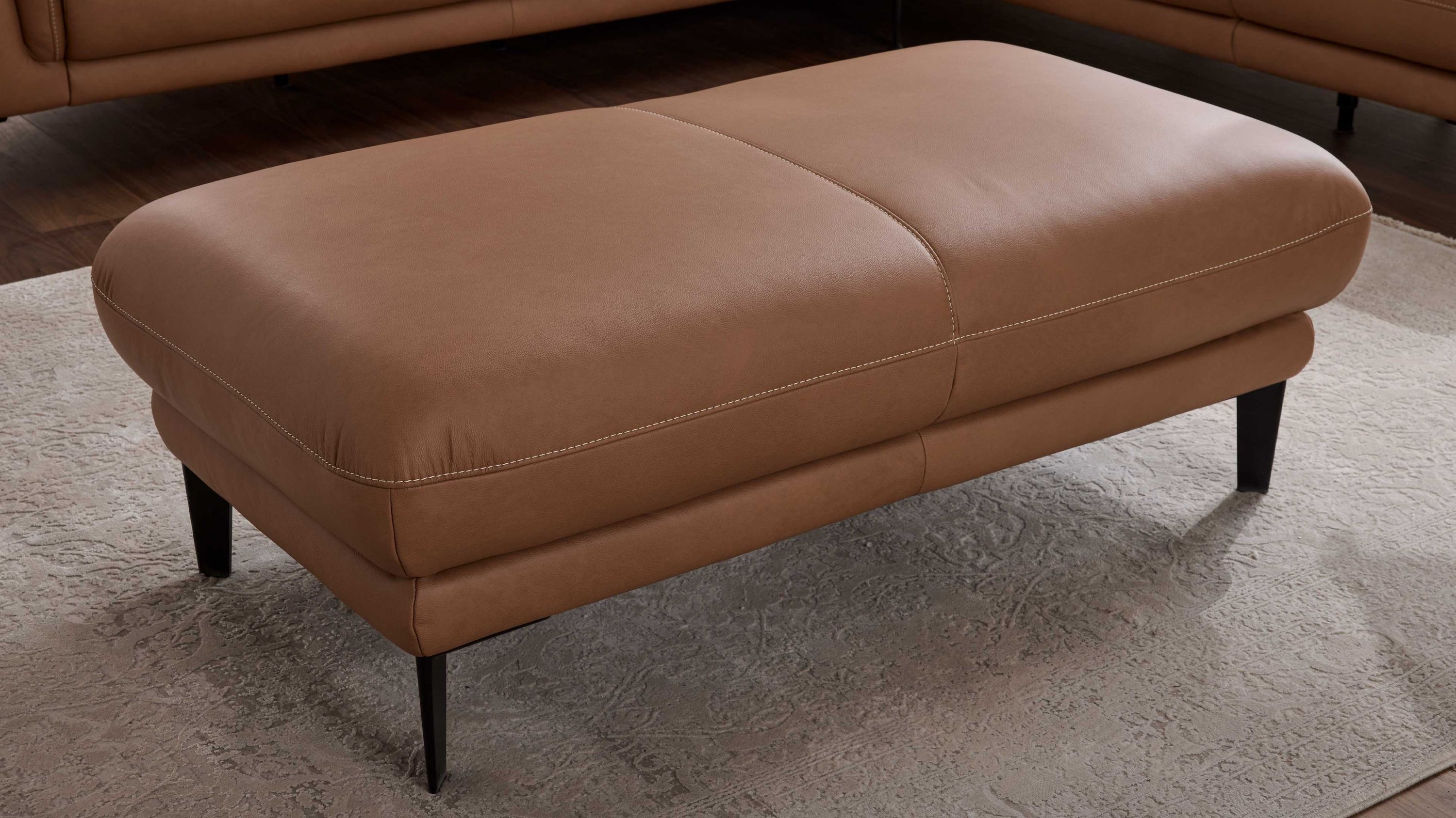 XXL-Hocker in haselnussbraun mit schwarzen Füßen Großer rechteckiger Hocker in haselnussbraun mit schwarzen schlanken Füßen auf hellem Teppich