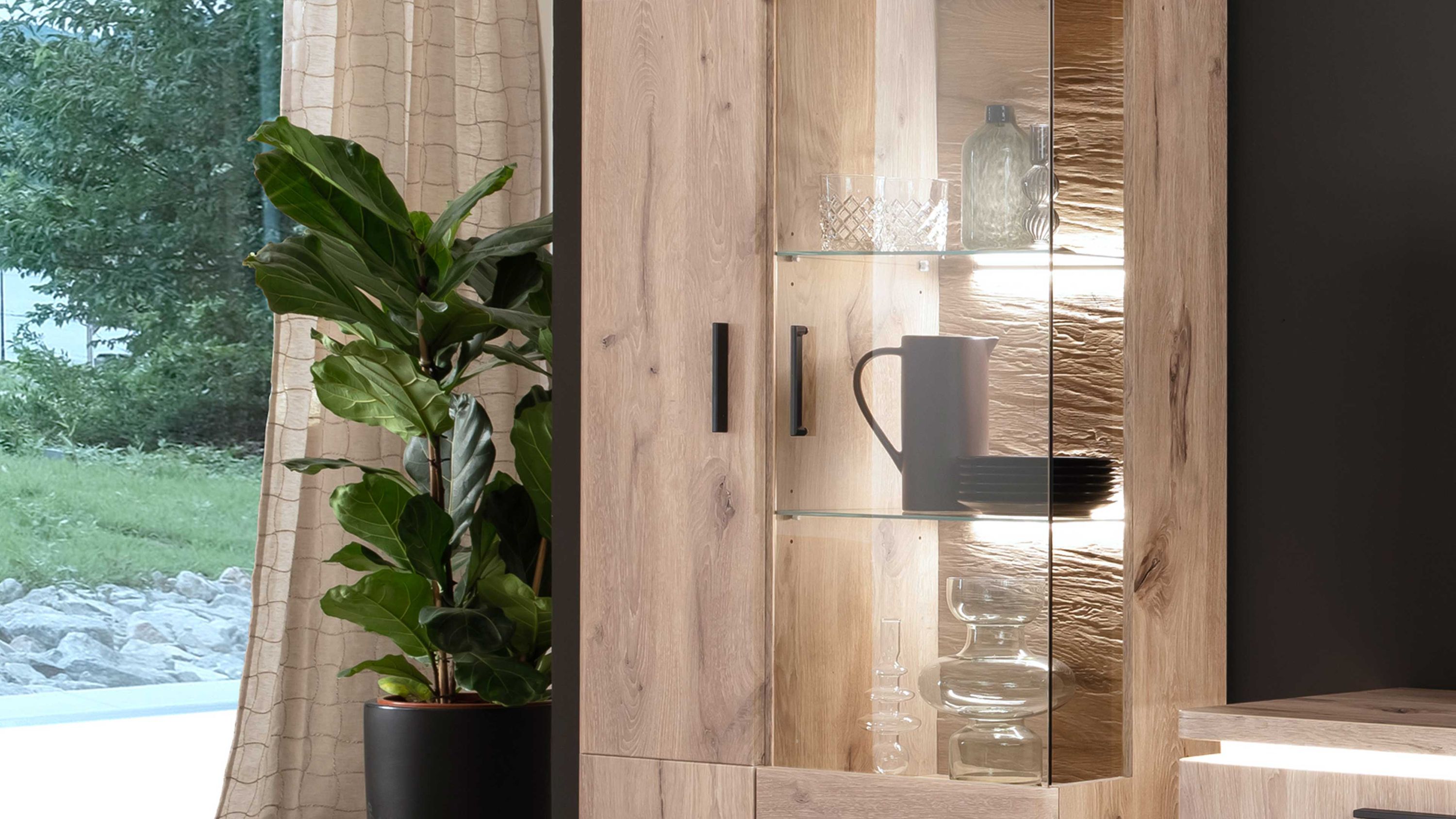 Zweiteilige Rückwandbeleuchtung in einer Vitrine mit Holzoptik und Glastüren beleuchtete Glasregale mit Geschirr