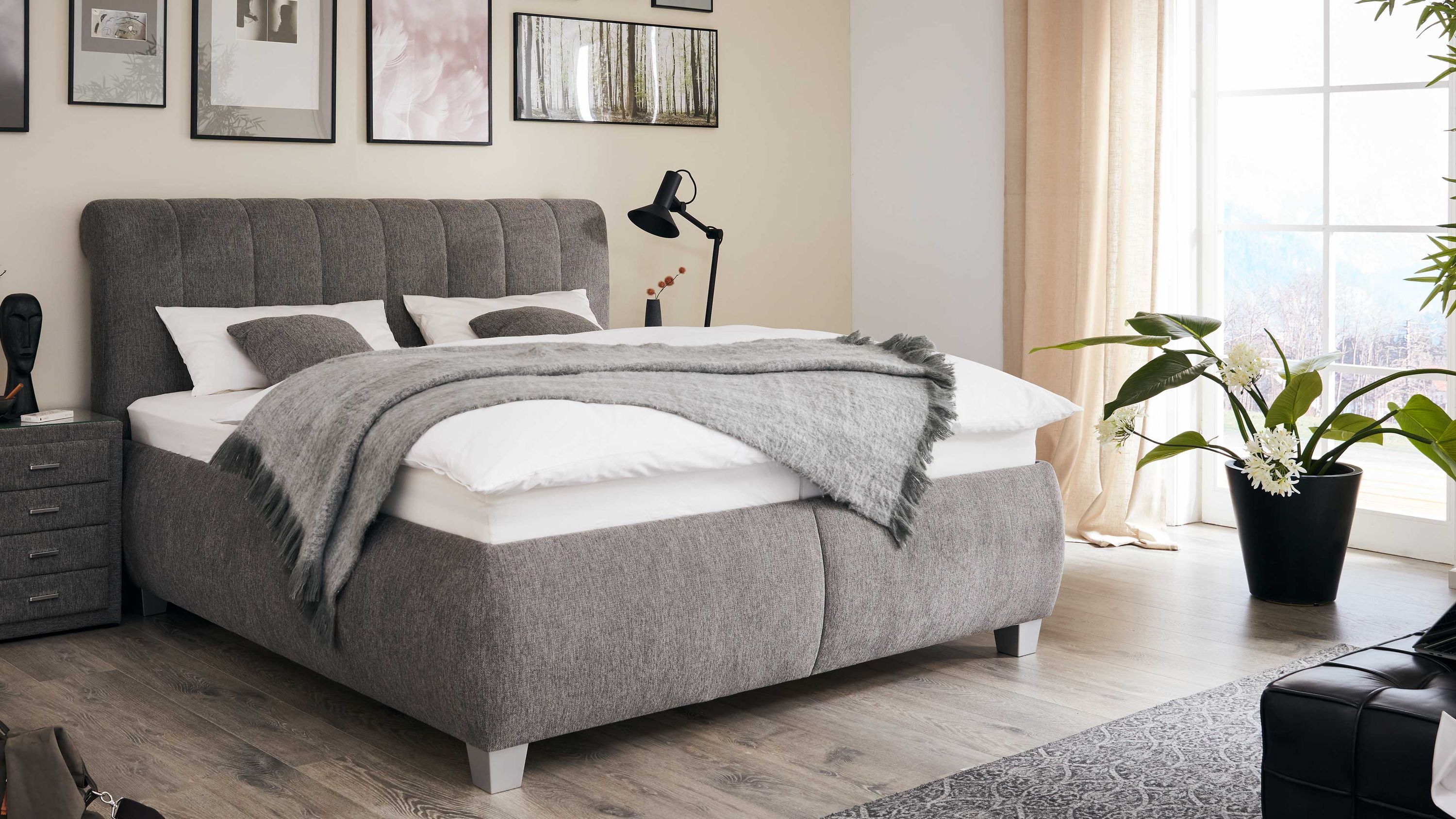 Graues Polsterbett mit gestepptem Kopfteil Graues Polsterbett mit gestepptem Kopfteil und grauer Decke in modernem Schlafzimmer