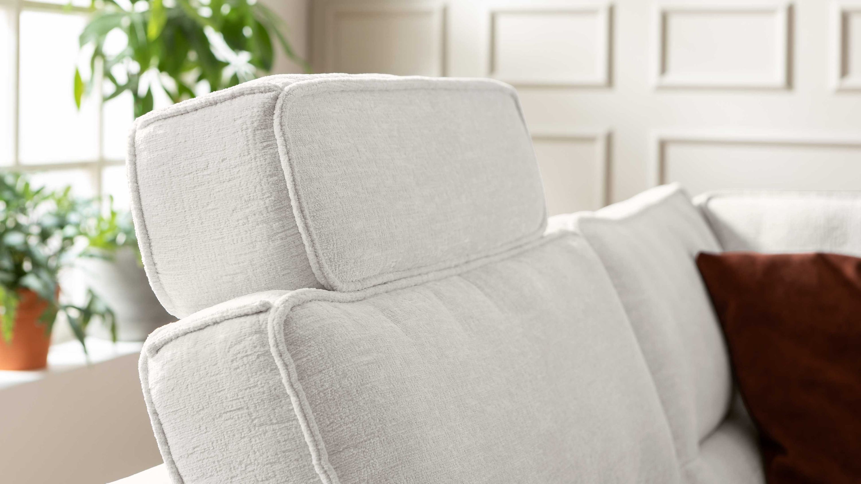 Naturweiße Kopfstütze aus Chenille auf einem hellen Sofa mit Kissen