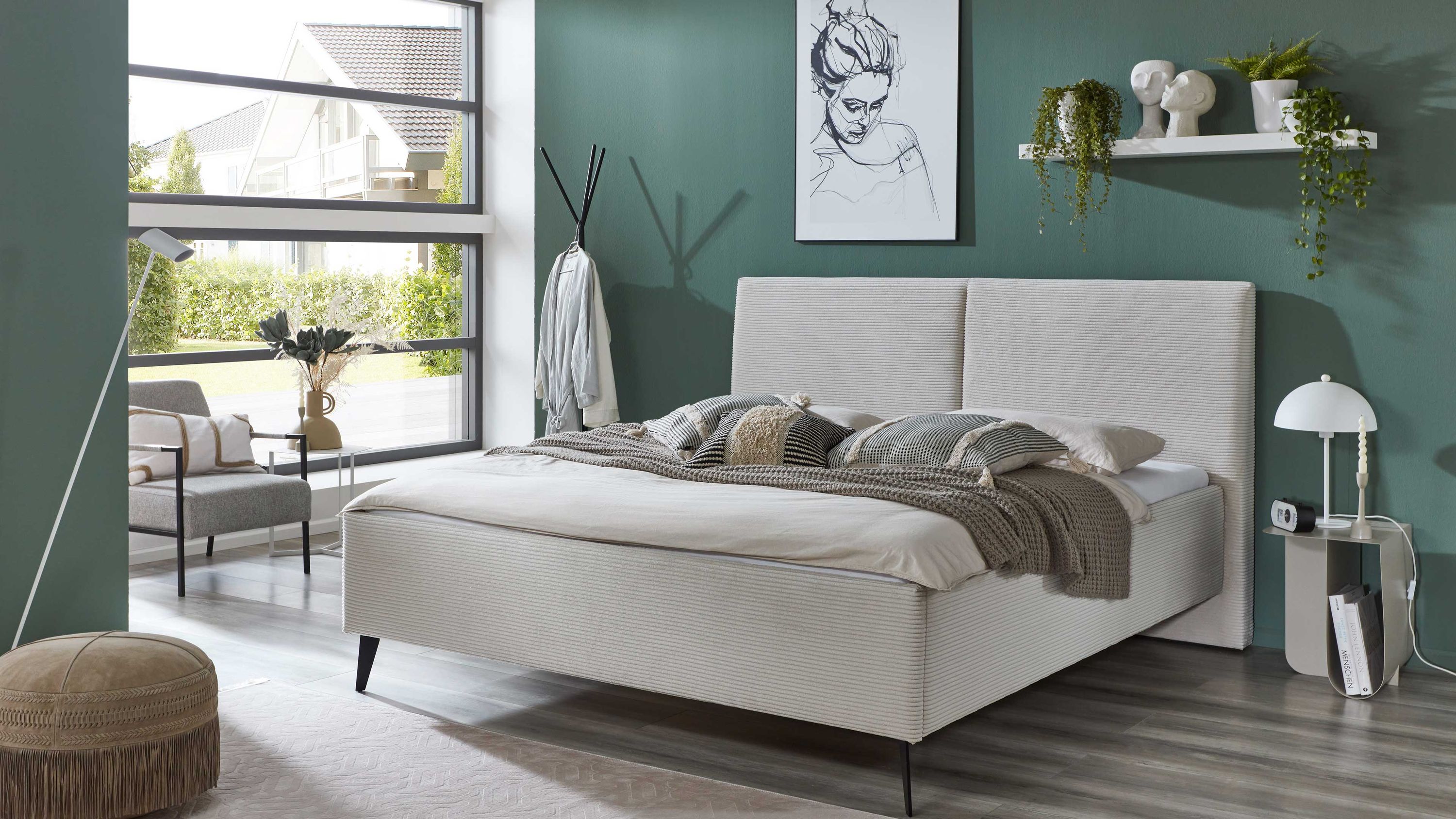 Beiges Polsterbett mit breitem Kopfteil schwarzen Metallfüßen und Bettkästen in modernem Schlafzimmer