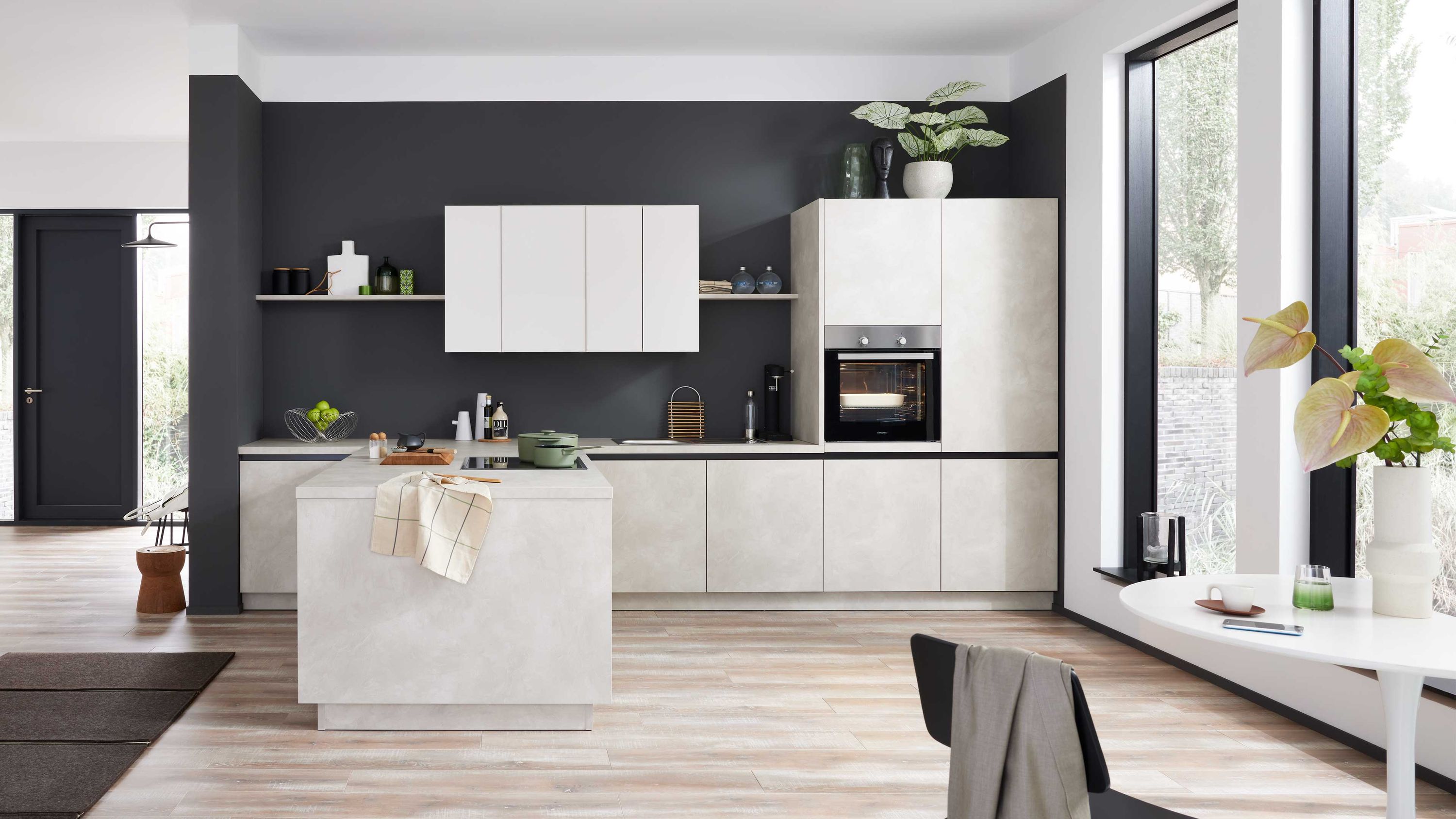 Küche mit hellen Fronten dunkler Wand Insel mit Spüle Holzfußboden Pflanzen und Fensterlicht