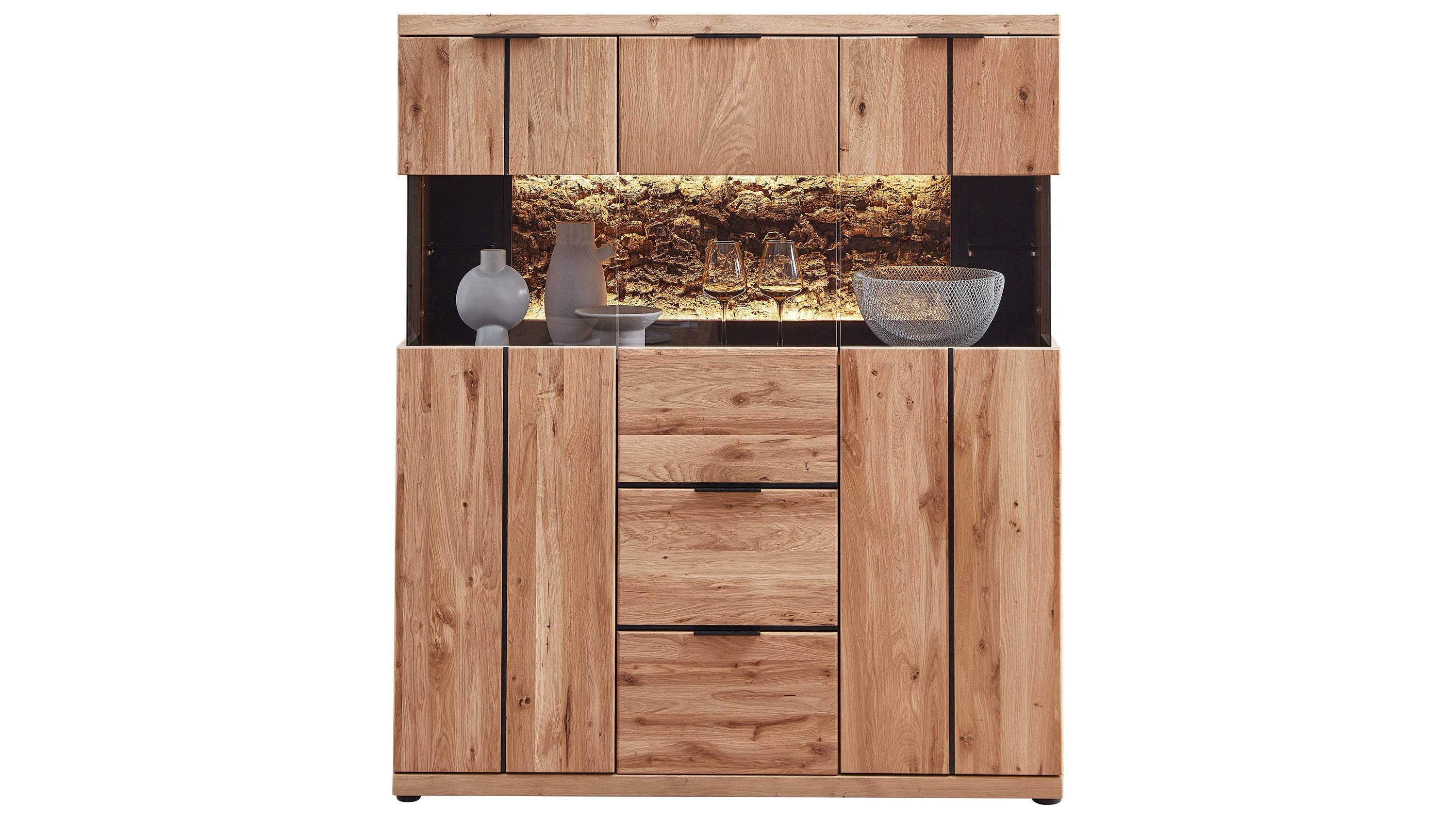 Highboard aus Holz mit drei Türen und zwei Schubladen mittig mit beleuchtetem Glasfach und Dekoration