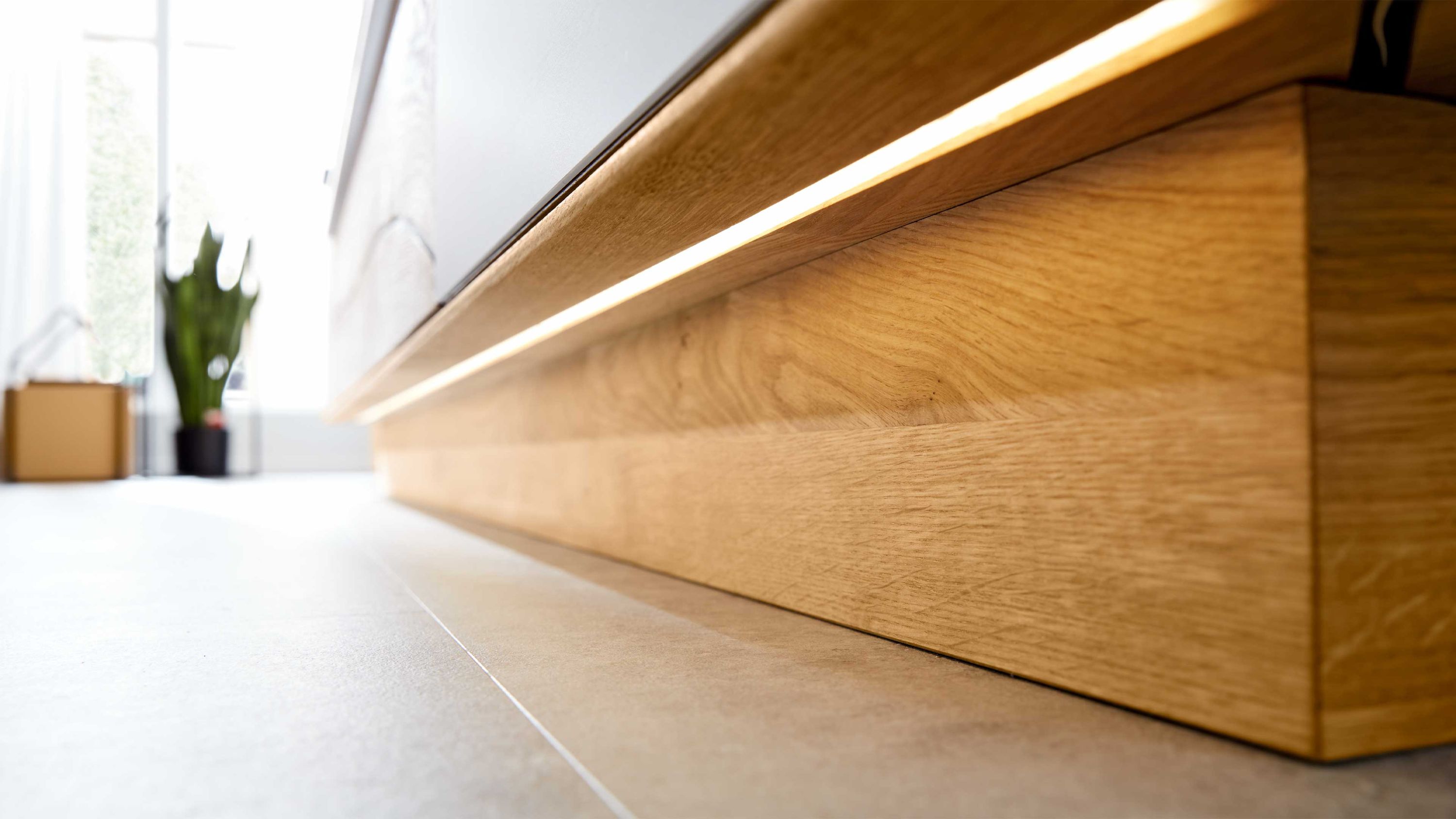 Unterbaubeleuchtung mit schmalem linearem Lichtstreifen an einem Möbel aus hellem Holz