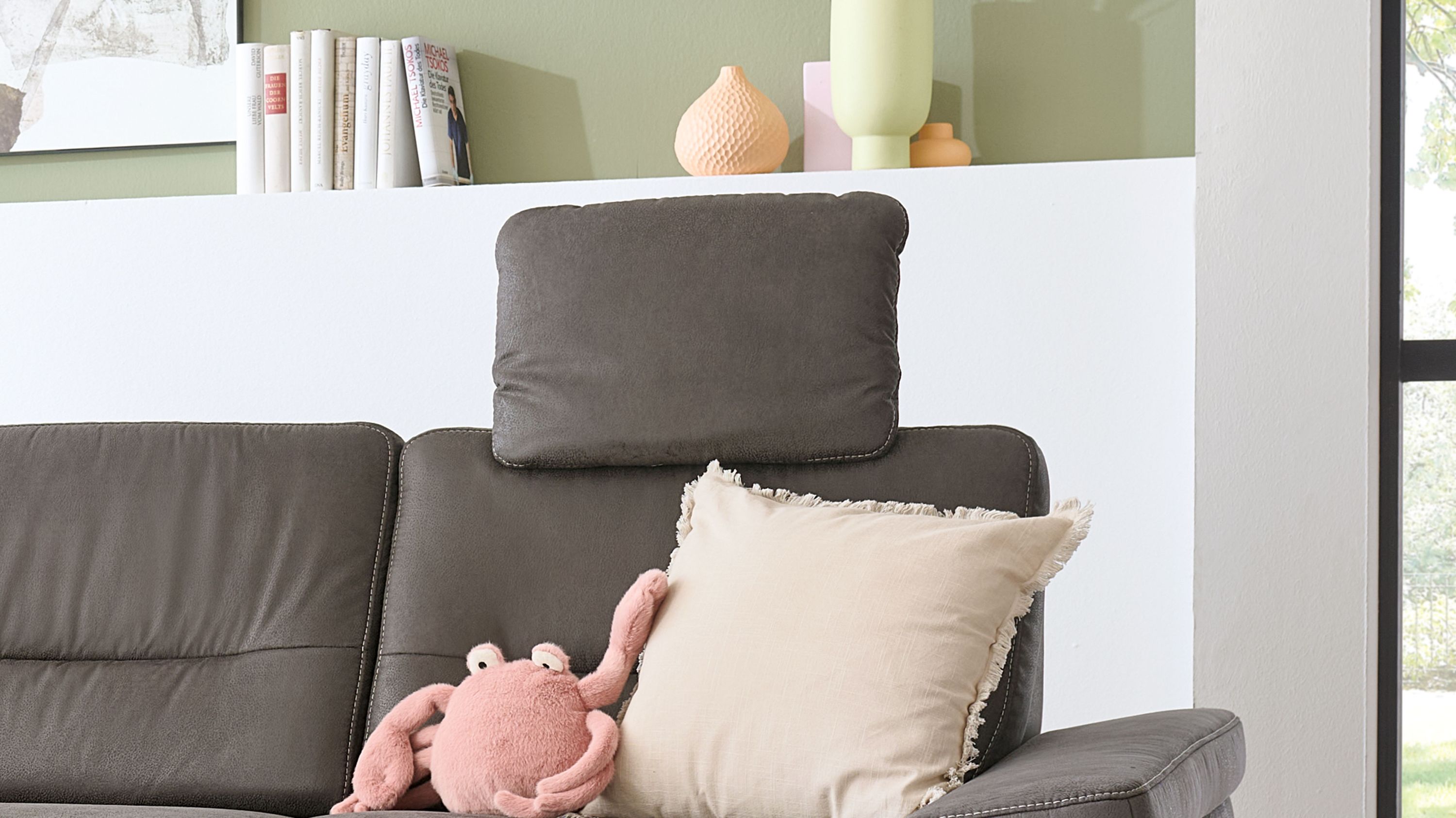 Anthrazitfarbene Kopfstütze mit rechteckiger Form auf einem dunkelgrauen Sofa