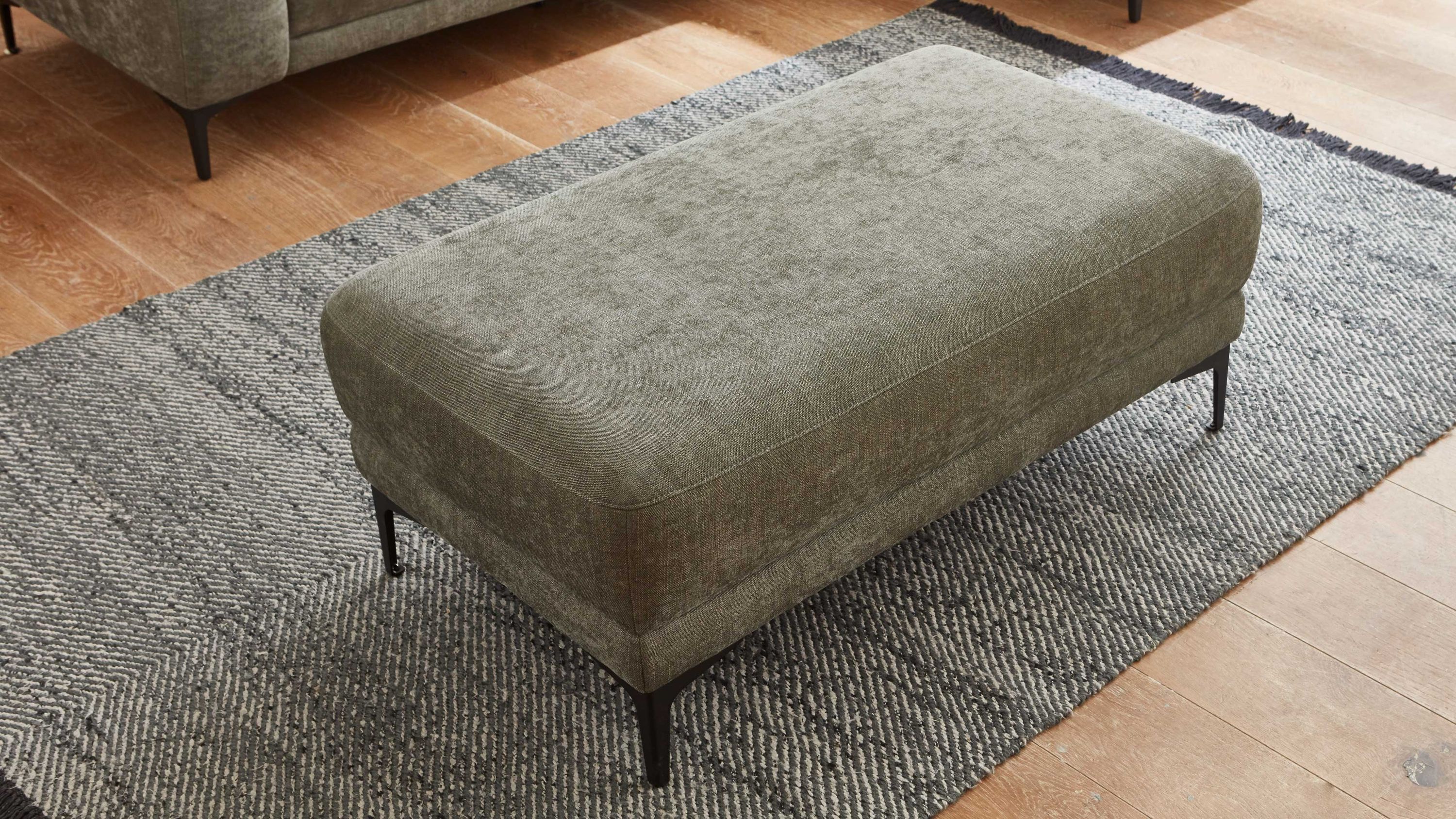 Rechteckiger Hocker mit grünem Stoffbezug und Metallfüßen Rechteckiger Hocker mit dunkelgrünem Strukturstoffbezug und schwarzen Metallfüßen auf grauem Teppich