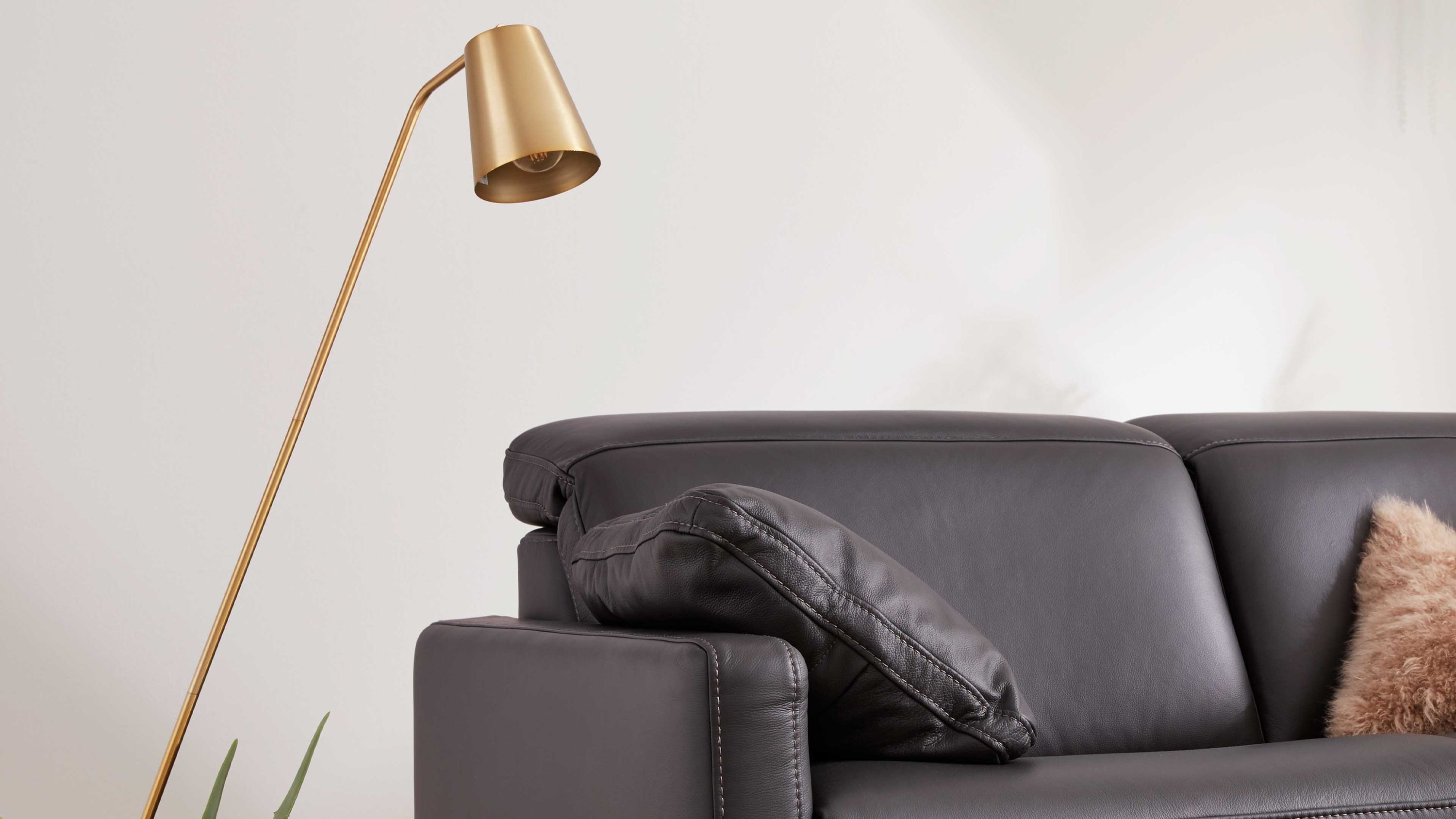 Dunkelgraues Armlehnkissen auf einem dunkelgrauen Sofa mit glatter Oberfläche