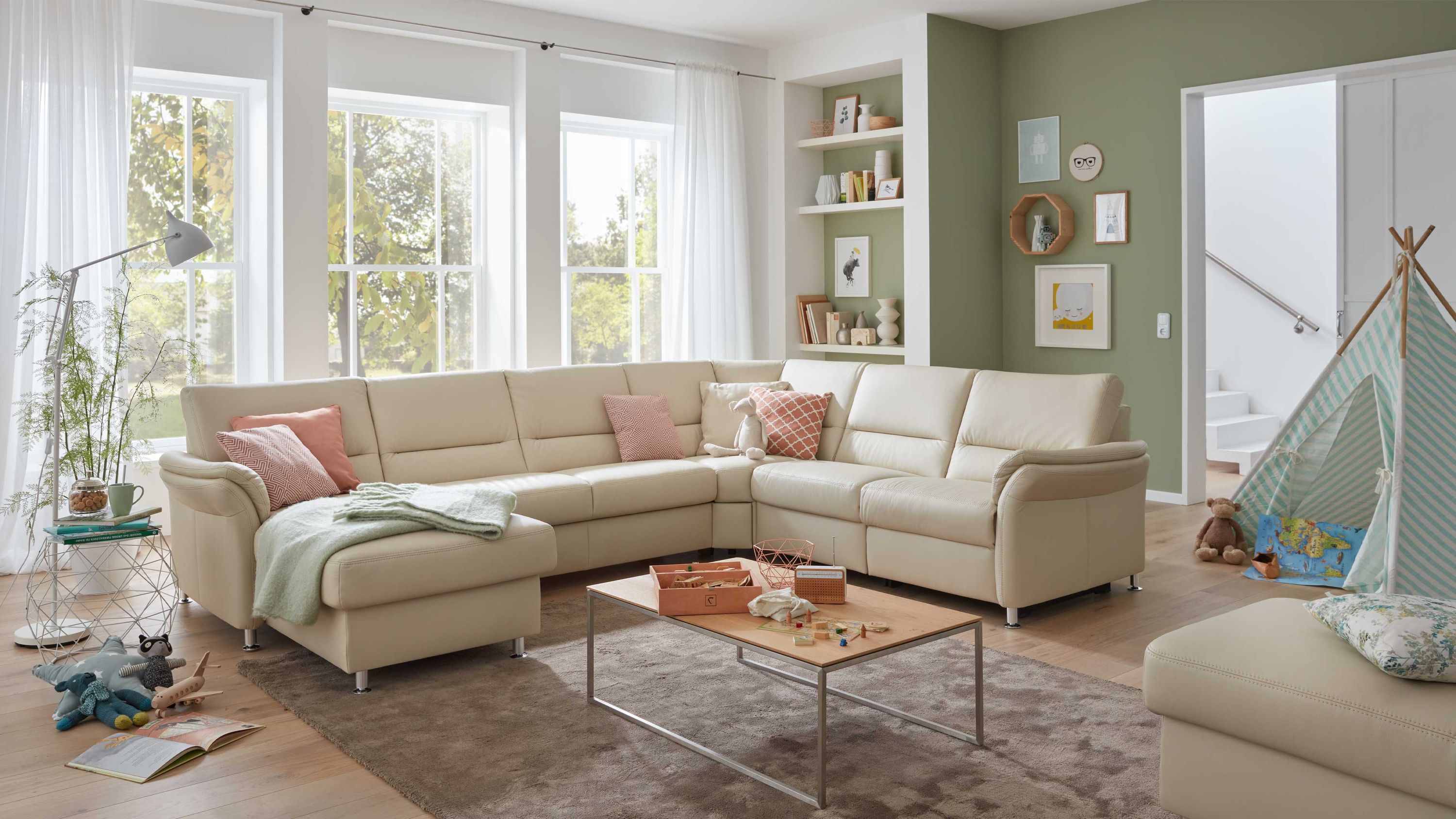 Ecksofa mit ecrufarbenem Lederbezug und Metallfüßen in einem hellen Wohnzimmer mit Teppich und Couchtisch