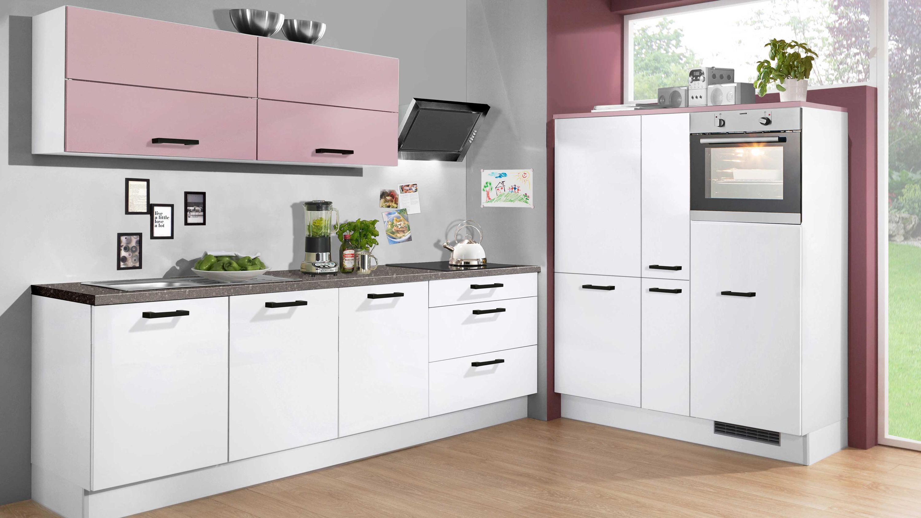 Küche mit rosa Oberschränken und integriertem Ofen Weiße Küche mit rosa Hängeschränken Einbauofen Arbeitsplatte mit Küchenutensilien Gemüse Gewürzgläsern.