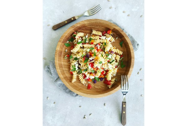 Holzschale mit gemischtem Salat  daneben liegen Messer und Gabel auf heller Tischdecke