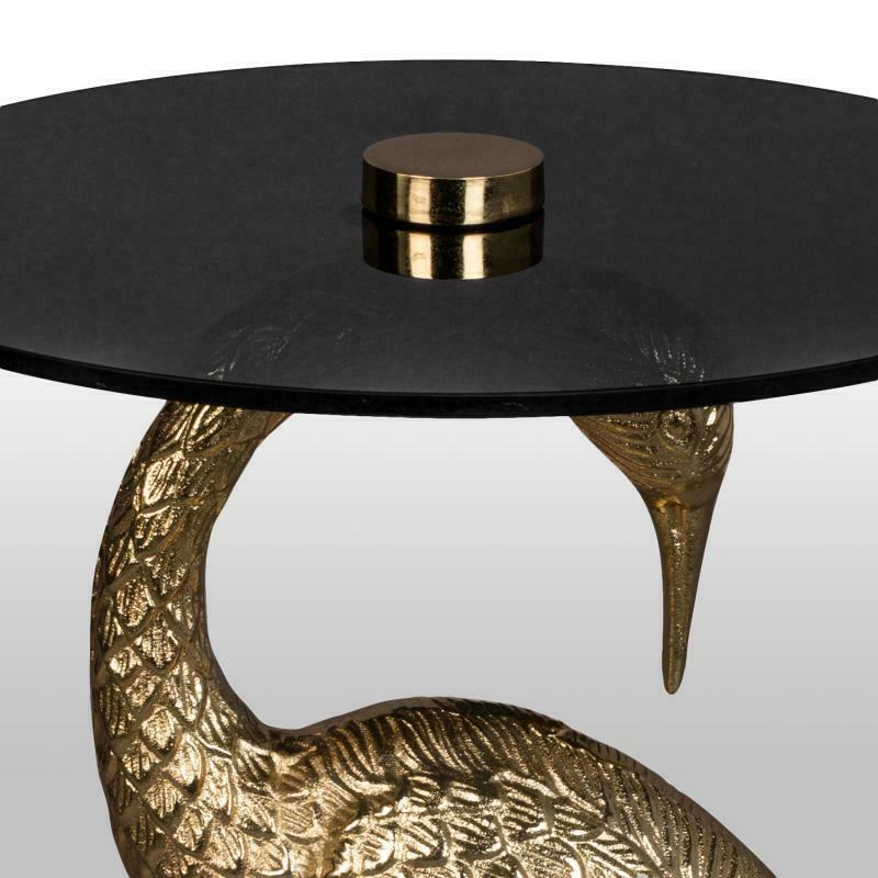 Detailansicht des schwarzen Glastischs mit goldener Kranichfigur  der Kopf ragt elegant unter die runde Tischplatte