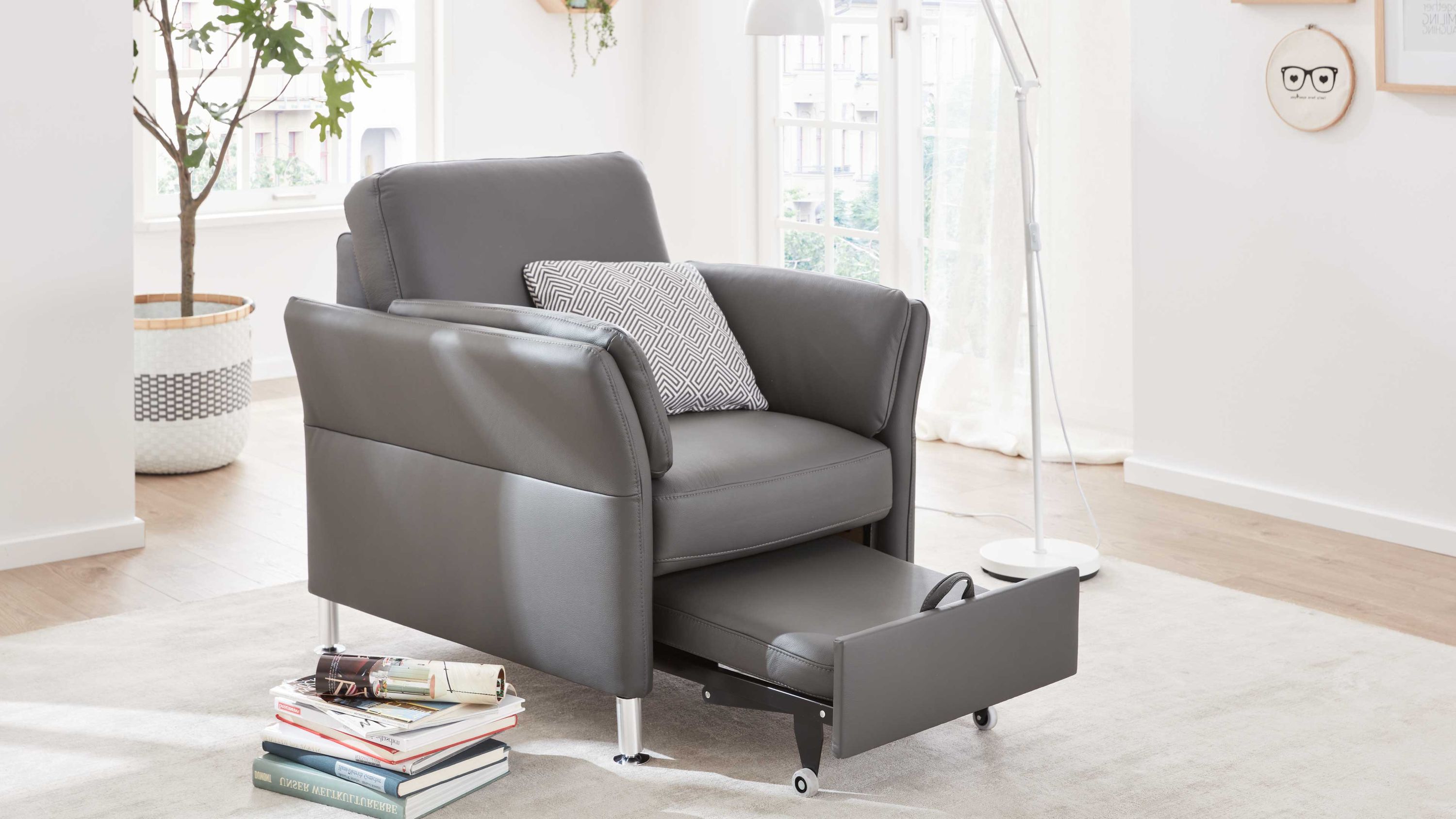 Anthrazitfarbener Sessel mit herausziehbarem Hocker und Aluminiumfüßen in hellem Raum