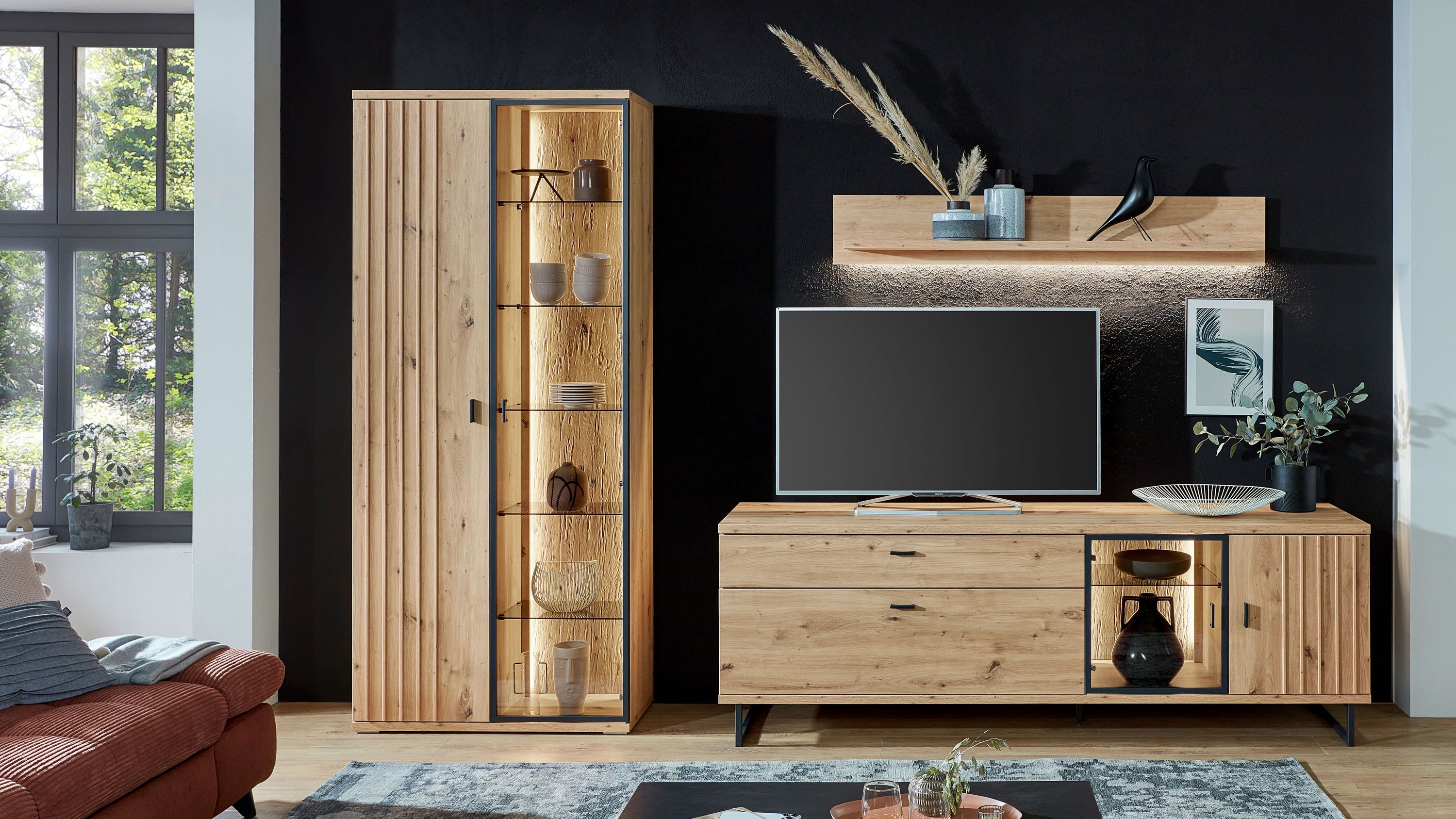 Dreiteilige Wohnwand in Holzoptik Dreiteilige Wohnwand mit Vitrine Sideboard und Wandregal in heller Holzoptik vor schwarzer Wand