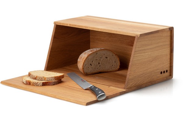 Holz-Brotkasten mit offenem Deckel, darauf zwei Brotscheiben und ein Messer, frontal leicht von oben aufgenommen.