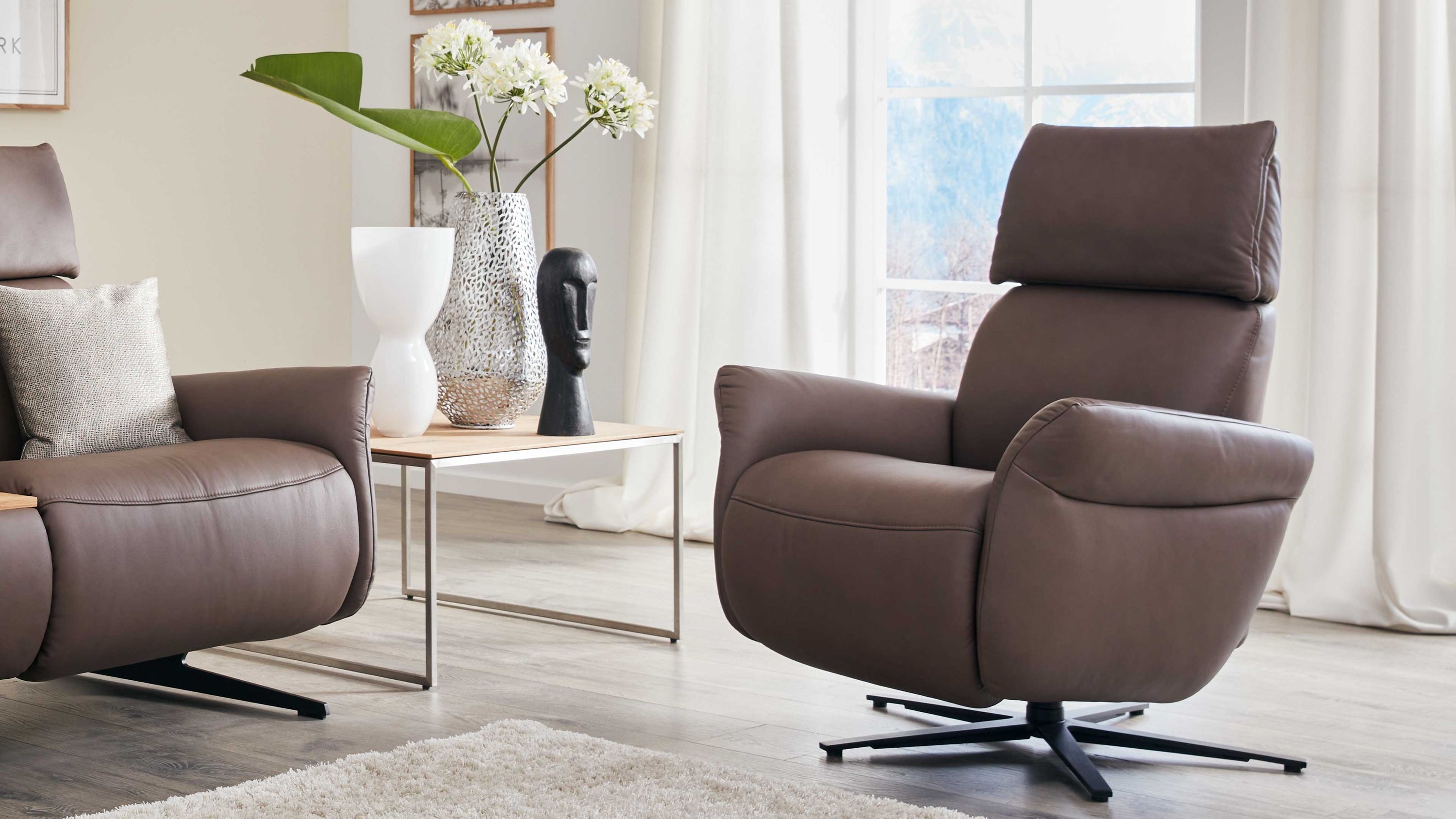 Brauner Relaxsessel mit Sternfuß Brauner Relaxsessel mit gepolstertem Kopfteil und anthrazitfarbenem Sternfuß in hellem Wohnzimmer