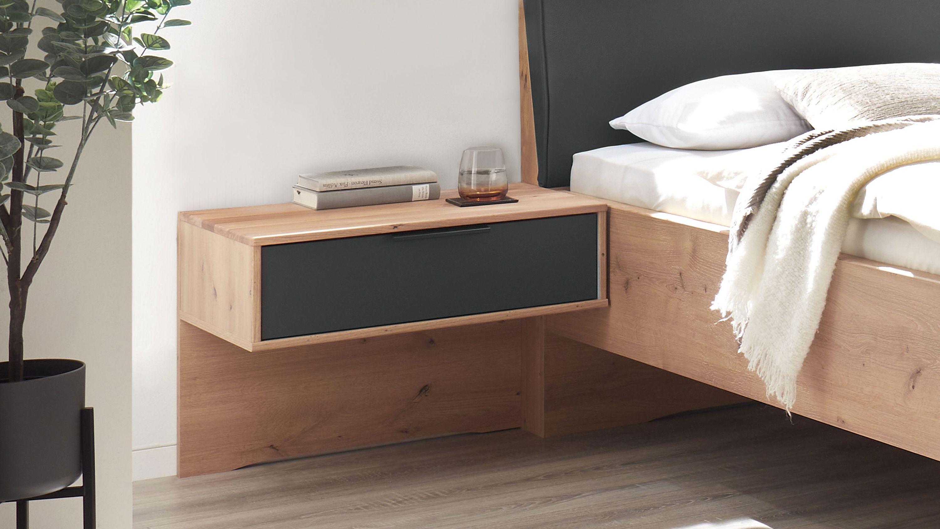 Zweiteilige Hängekonsole mit Schublade in graphit und Eichefarben neben einem Bett mit Kopfteil