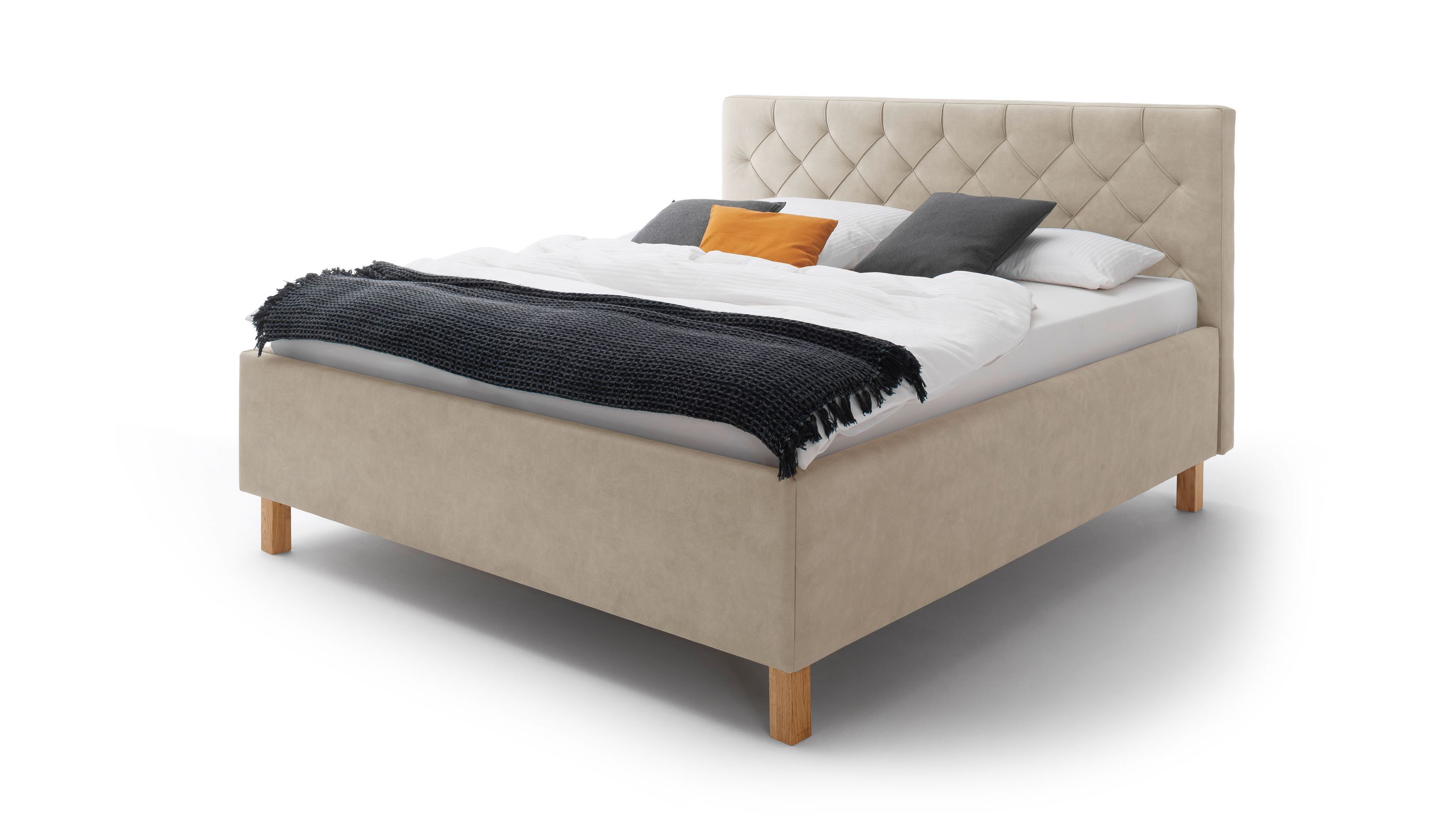 Beiges Polsterbett mit gesteppter Kopfteilfläche und Holzfüßen Beiges Polsterbett mit gesteppter Kopfteilfläche und eichefarbenen Holzfüßen mit Decke und Kissen belegt