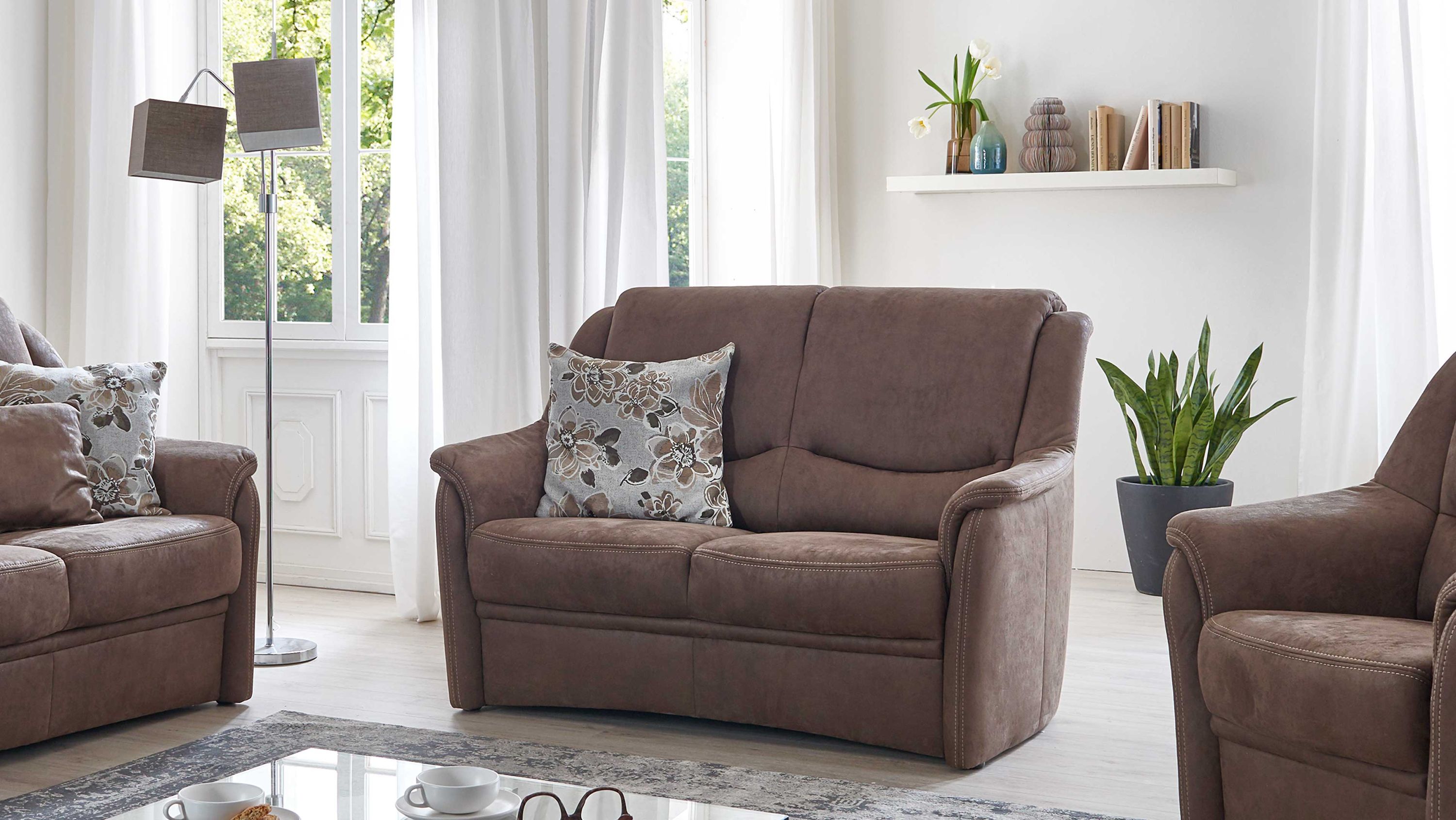 Zweisitziges Sofa in brauner Mikrofaser mit gepolsterten Armlehnen und floral gemustertem Kissen