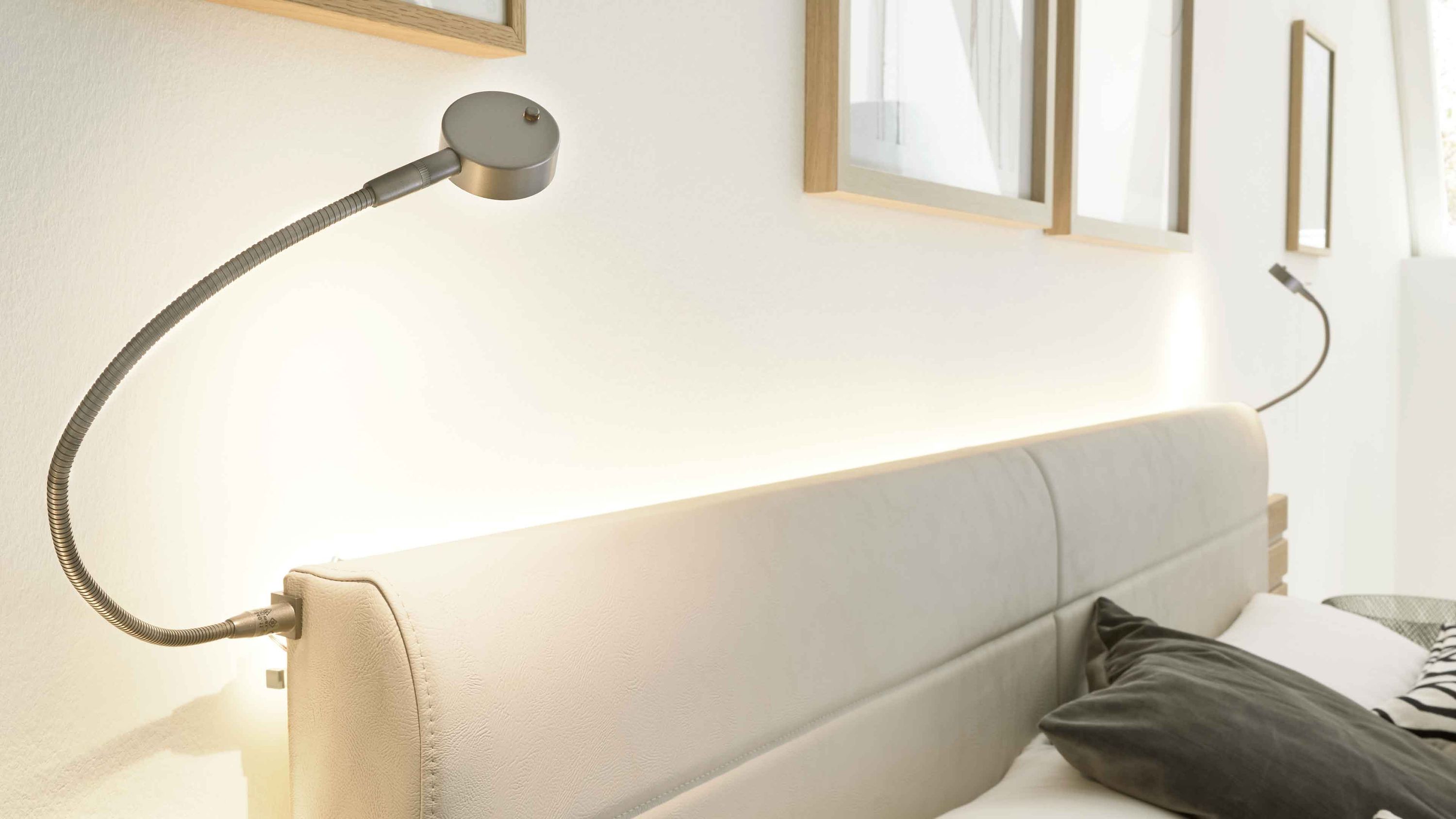 Zweiteiliges Flexleuchten-Set mit zwei gebogenen Leselampen in Metallfarbe an einem gepolsterten Kopfteil in hellbeige