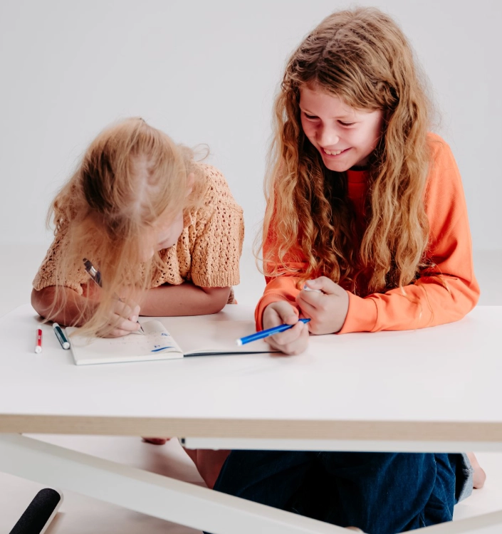 zwei mädchen poptop Zwei Kinder malen lachend an weißem höhenverstellbaren Schreibtisch und nutzen ihn kreativ zum gemeinsamen Lernen und Spielen.