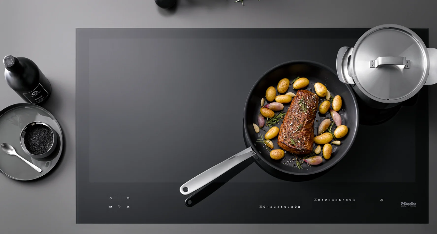 Miele Küche – Mobile Headerbild Kompaktes Headerbild mit Kochfeld, Töpfen und Zutaten auf dunkler Fläche, mobile Optimierung