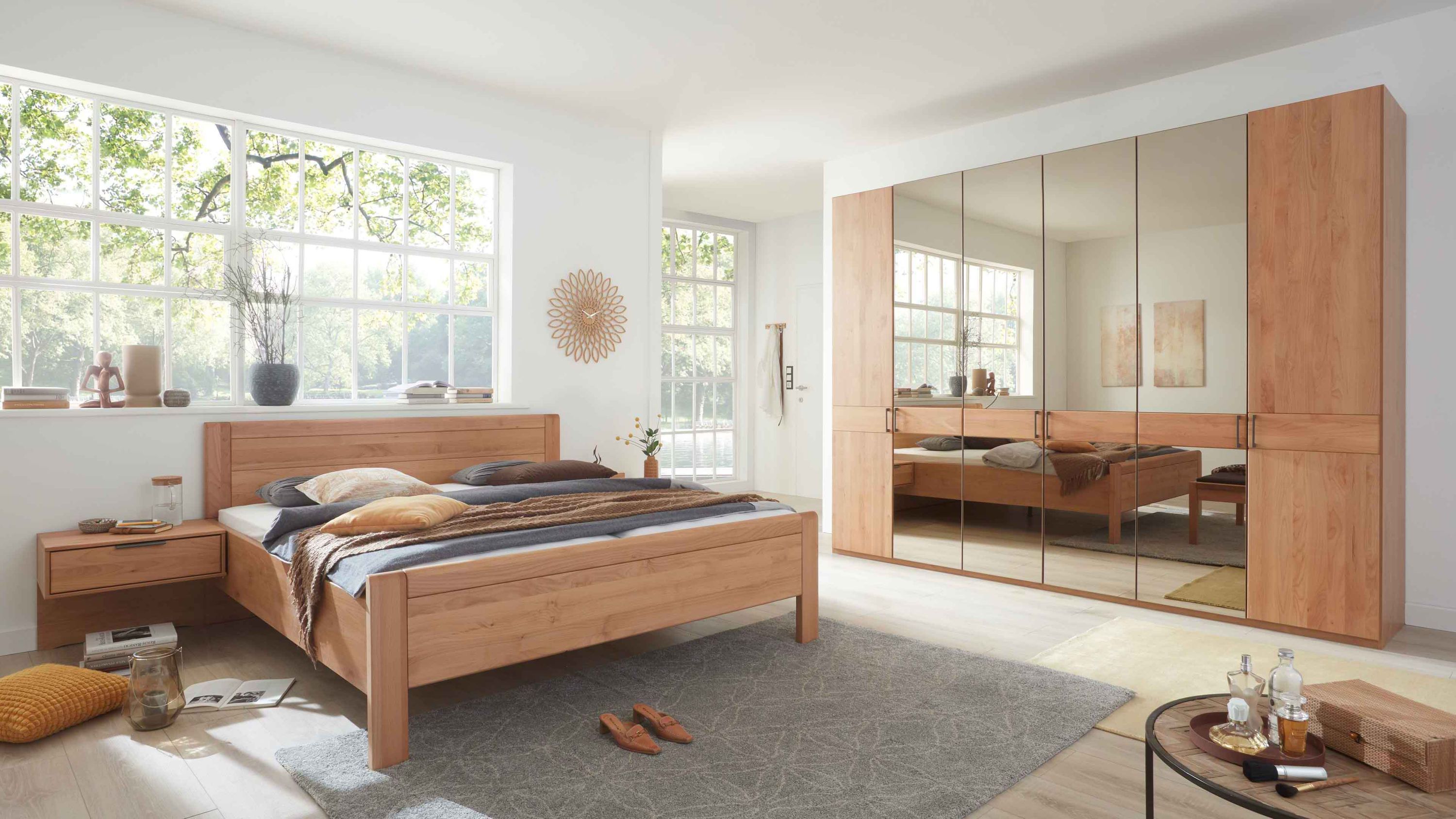 Schlafzimmer mit Holzbett zwei Nachttischen und großem Kleiderschrank mit Spiegeltüren in hellem Holz