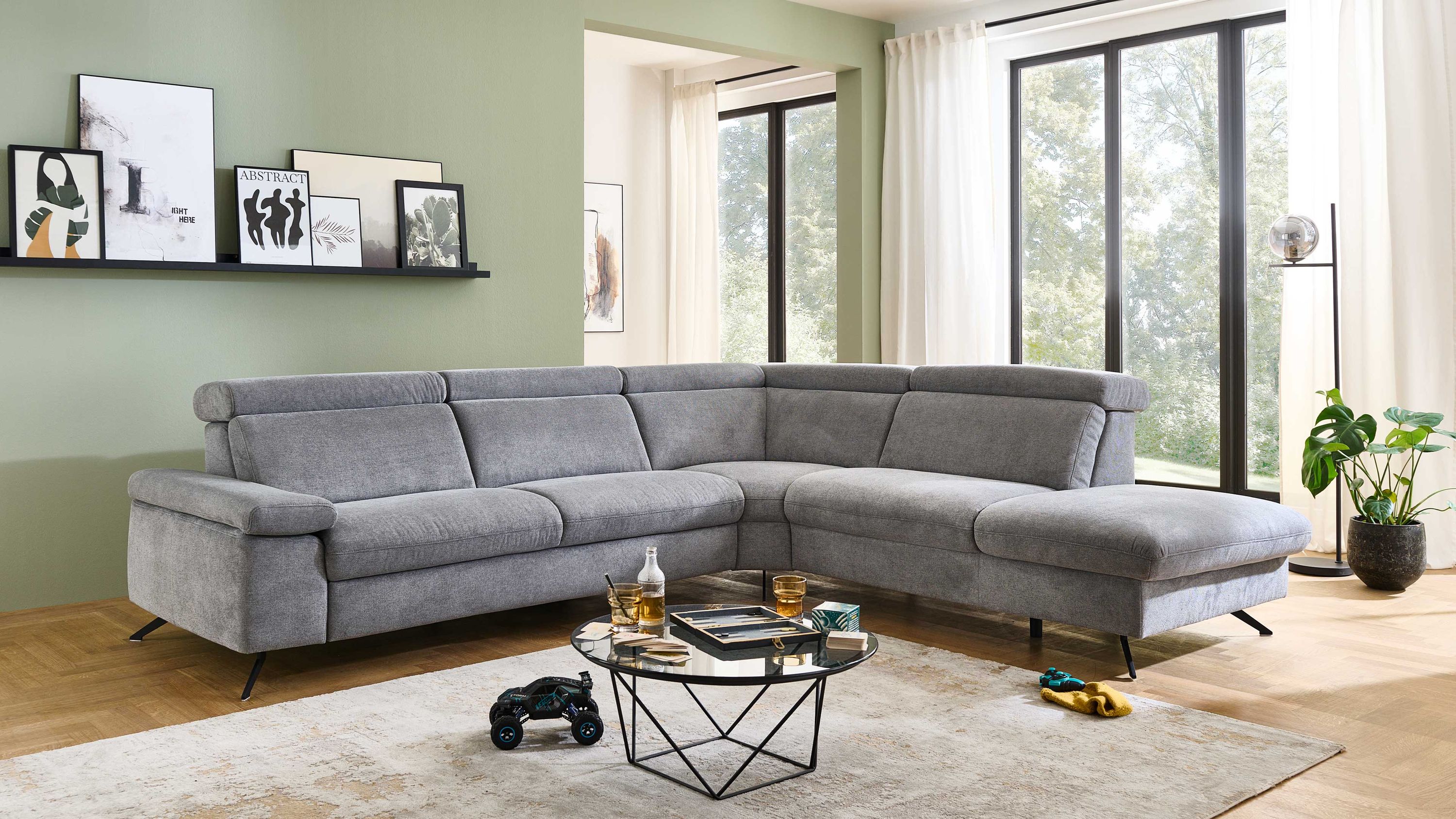 Ecksofa mit grauem Flachgewebe und schwarzen Metallfüßen in modernem Wohnzimmer mit großen Fenstern
