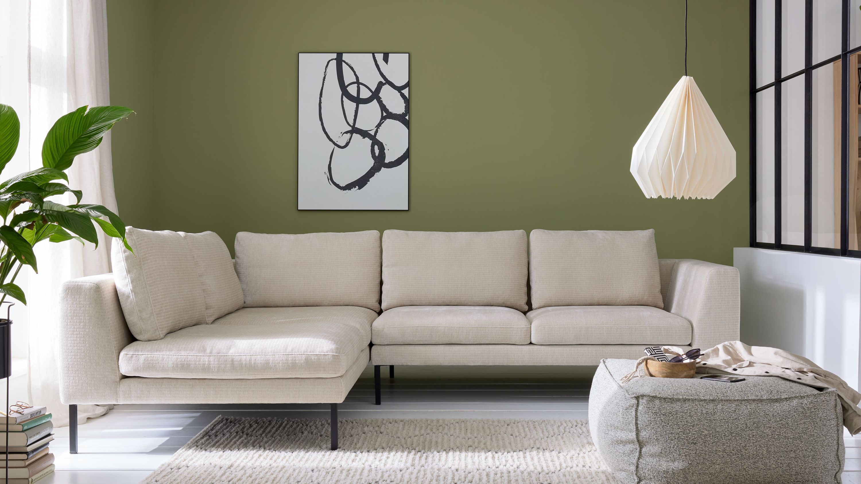 Ecksofa mit naturfarbenem Bezug und schwarzen Metallfüßen in modernem Wohnzimmer mit grünem Hintergrund