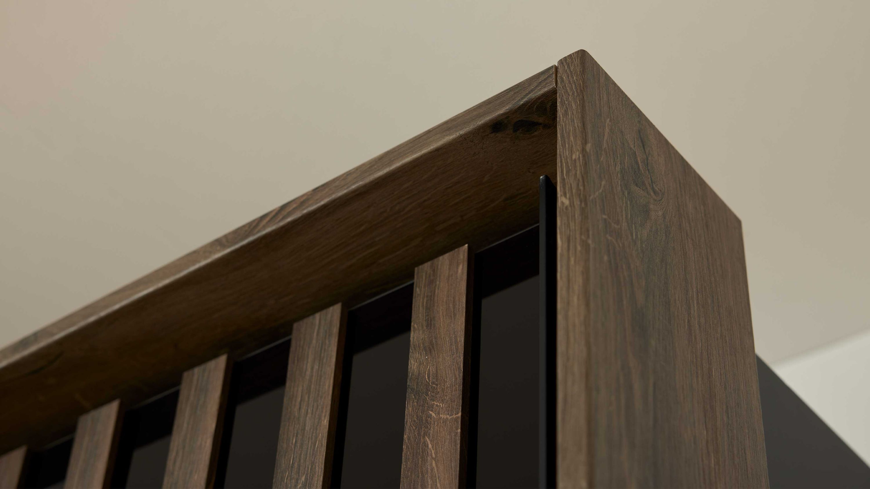 Kleiderschrank mit vertikalen Holzlamellen in dunkler Holzoptik Eckansicht eines Kleiderschranks mit vertikalen Holzlamellen in dunkler Holzoptik und schwarzen Zwischenräumen