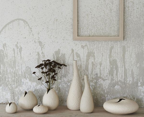 Beige Vasen und Blumentöpfe in verschiedenen Formen  teils mit Trockenblumen  vor strukturierter Wand mit leerem Rahmen