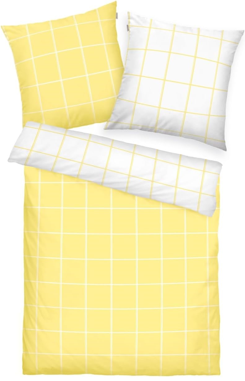 Draufsicht auf Bett mit zwei Kissen und Decke in Gelb-Weiß beidseitig kariert gestreift horizontal und vertikal