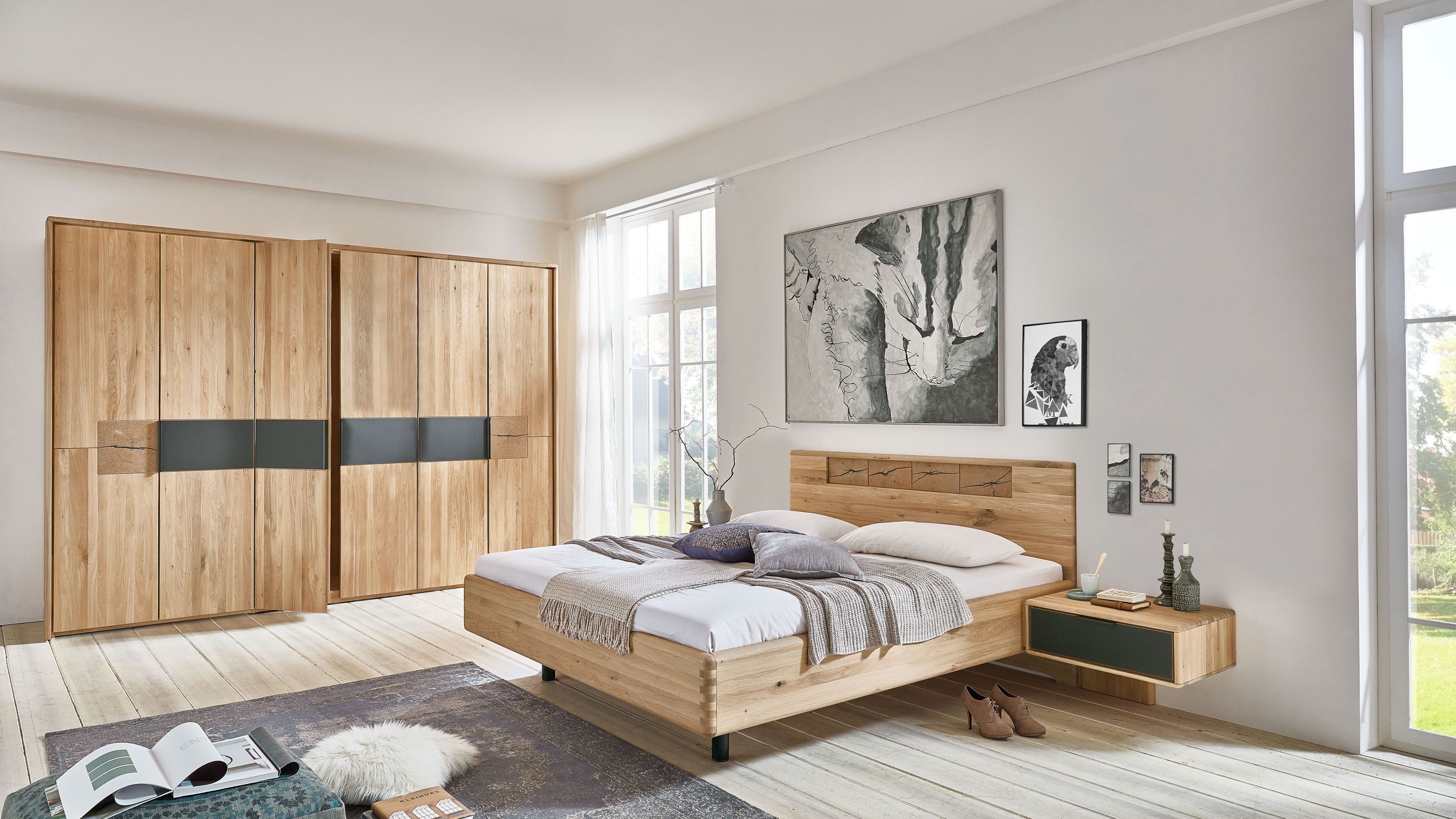 Schlafzimmer mit Bett aus hellem Holz zwei großen Kleiderschränken mit schwarzen Akzenten und einem schwebenden Nachttisch