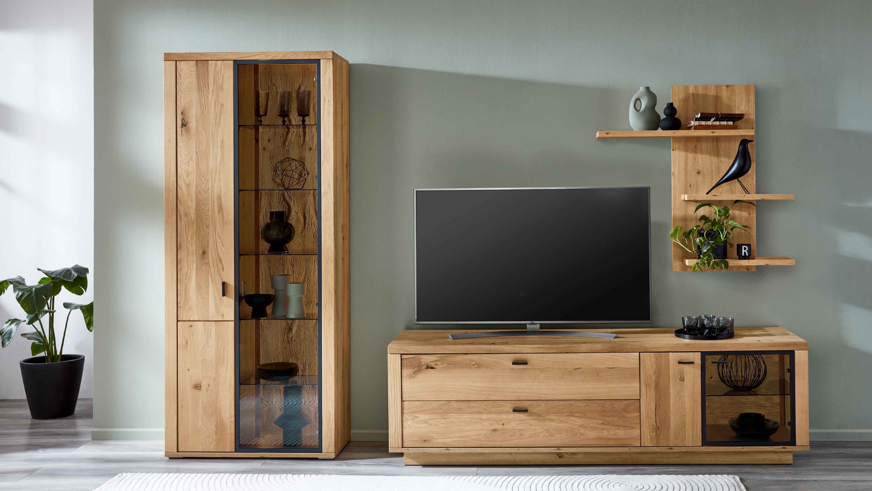 Dreiteilige Wohnwand aus hellem Holz mit Vitrine und TV-Board Dreiteilige Wohnwand aus hellem Holz mit Vitrine TV-Board und Wandregal mit Dekoration