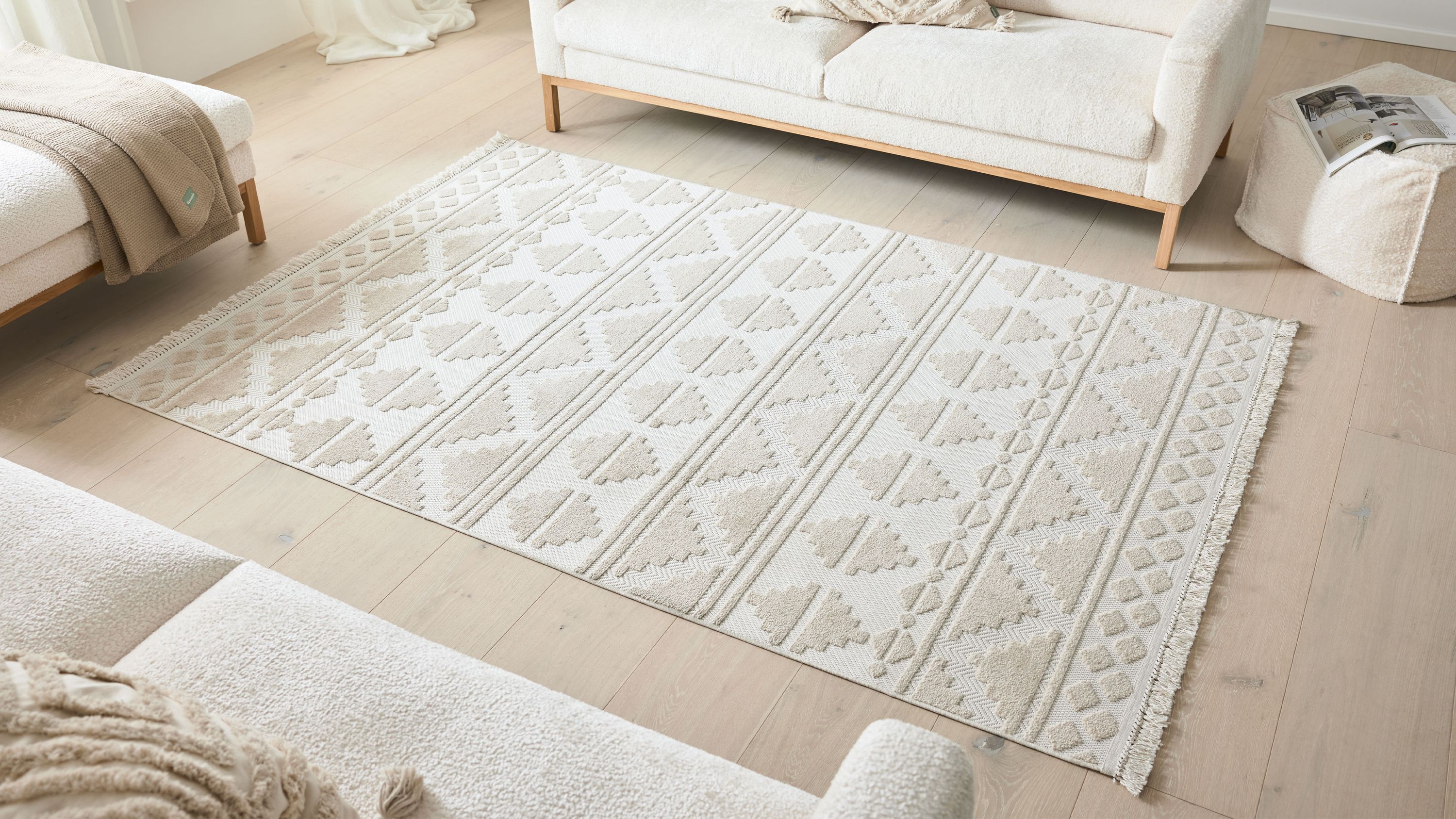 Beiger Teppich mit Rautenmuster auf hellem Holzboden zwischen weißen Sofas
