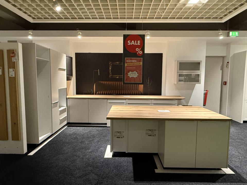 Moderne Küchenzeile mit weißen Schränken und Holzarbeitsplatten, zentrale Insel und dunkler Wand im Hintergrund