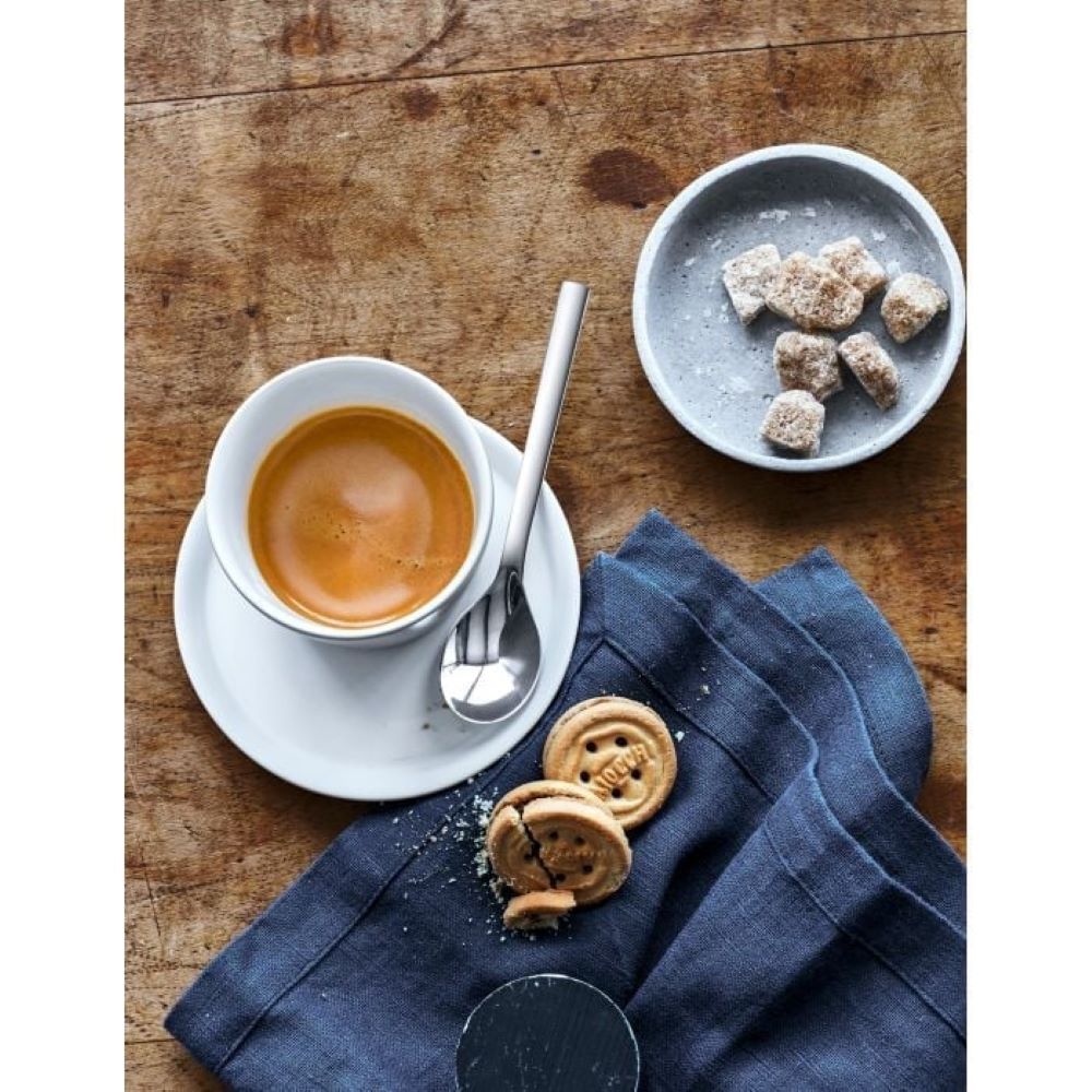 Tasse Kaffee mit Löffel Zuckerteller und Keksen auf blauer Serviette alles auf Holzoberfläche arrangiert Draufsicht