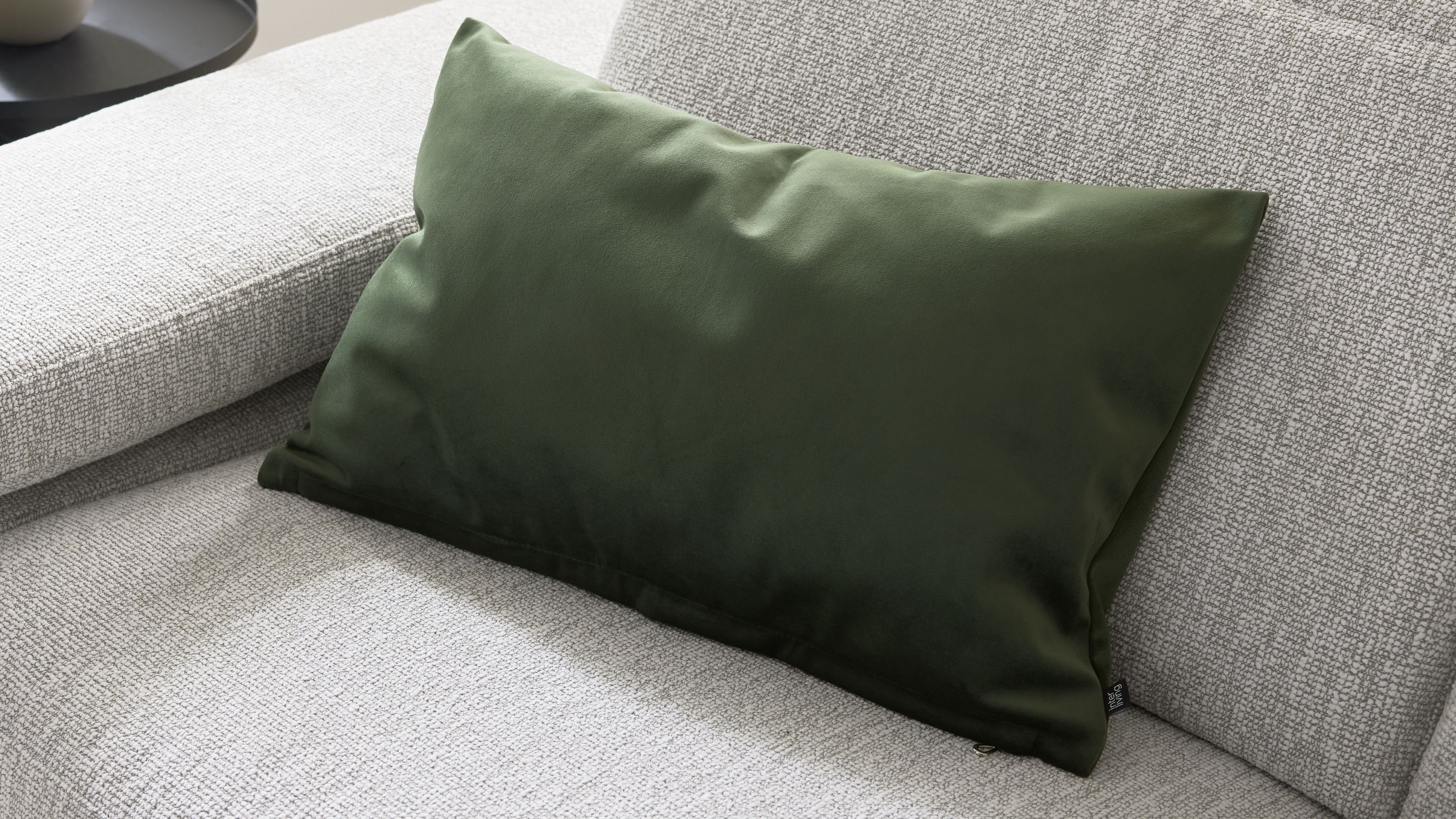 Rechteckiges Kissen in olivgrün auf hellgrauem Sofa