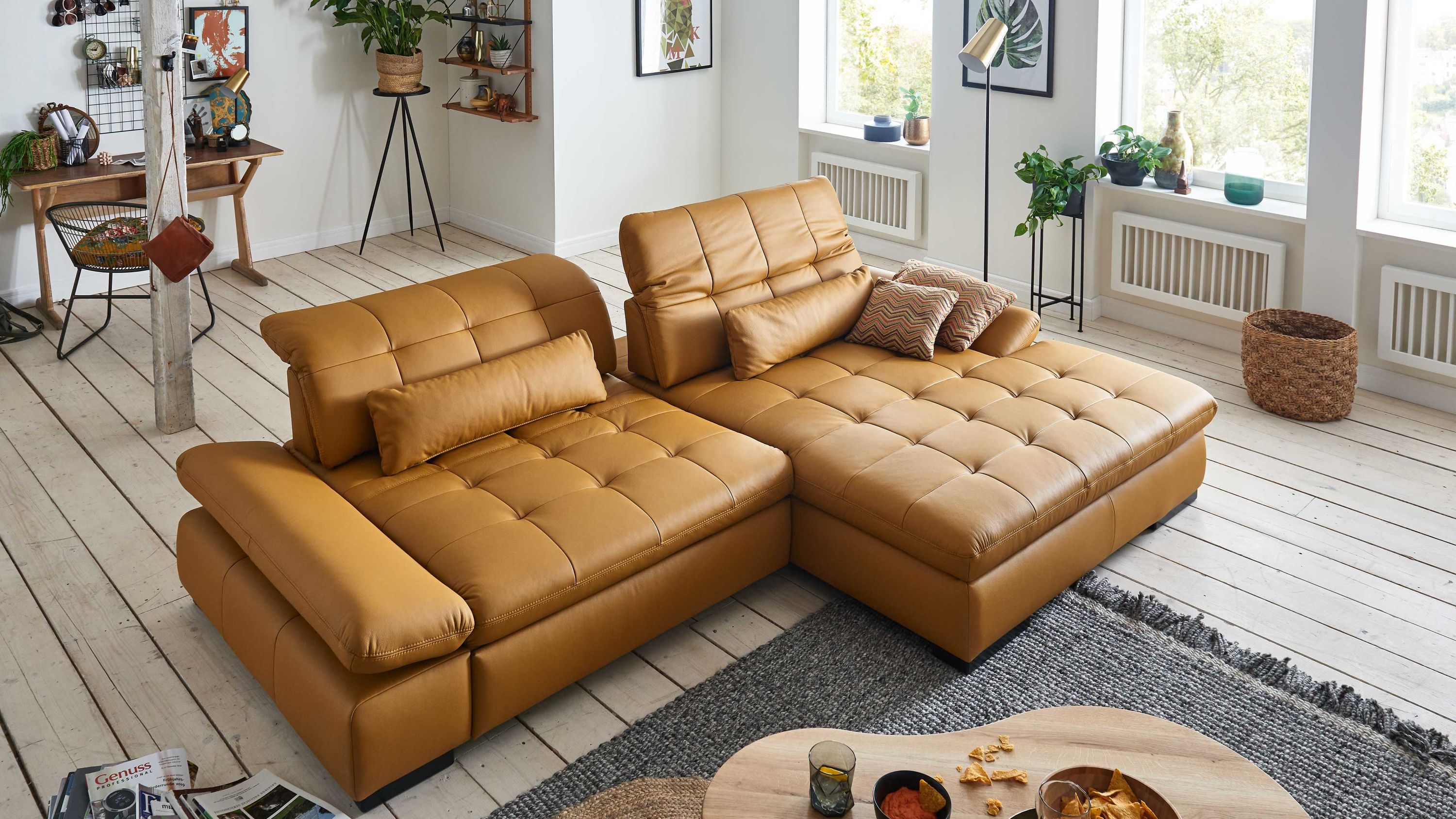 Ecksofa mit verstellbaren Rückenlehnen und schwarzen Holzfüßen in senffarbenem Leder in einem hellen Wohnzimmer