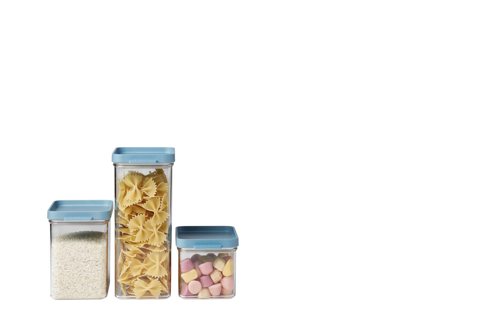 Drei transparente Dosen mit blauem Deckel, gefüllt mit Mehl, Pasta und bunten Süßigkeiten, frontal aufgenommen.