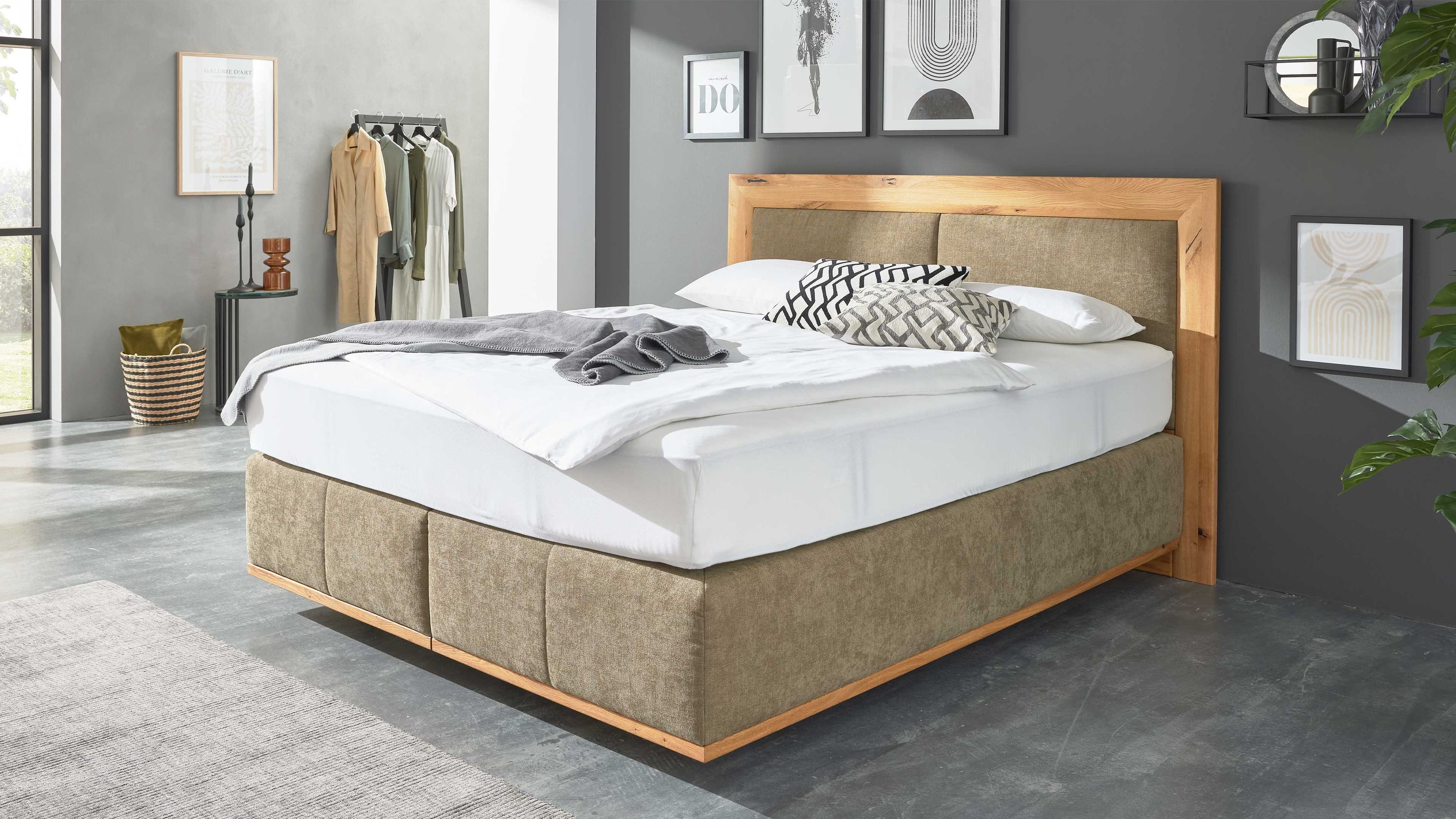 Boxspringbett mit olivgrünem Stoffbezug und Holzrahmen am Kopfteil in modernem Schlafzimmer