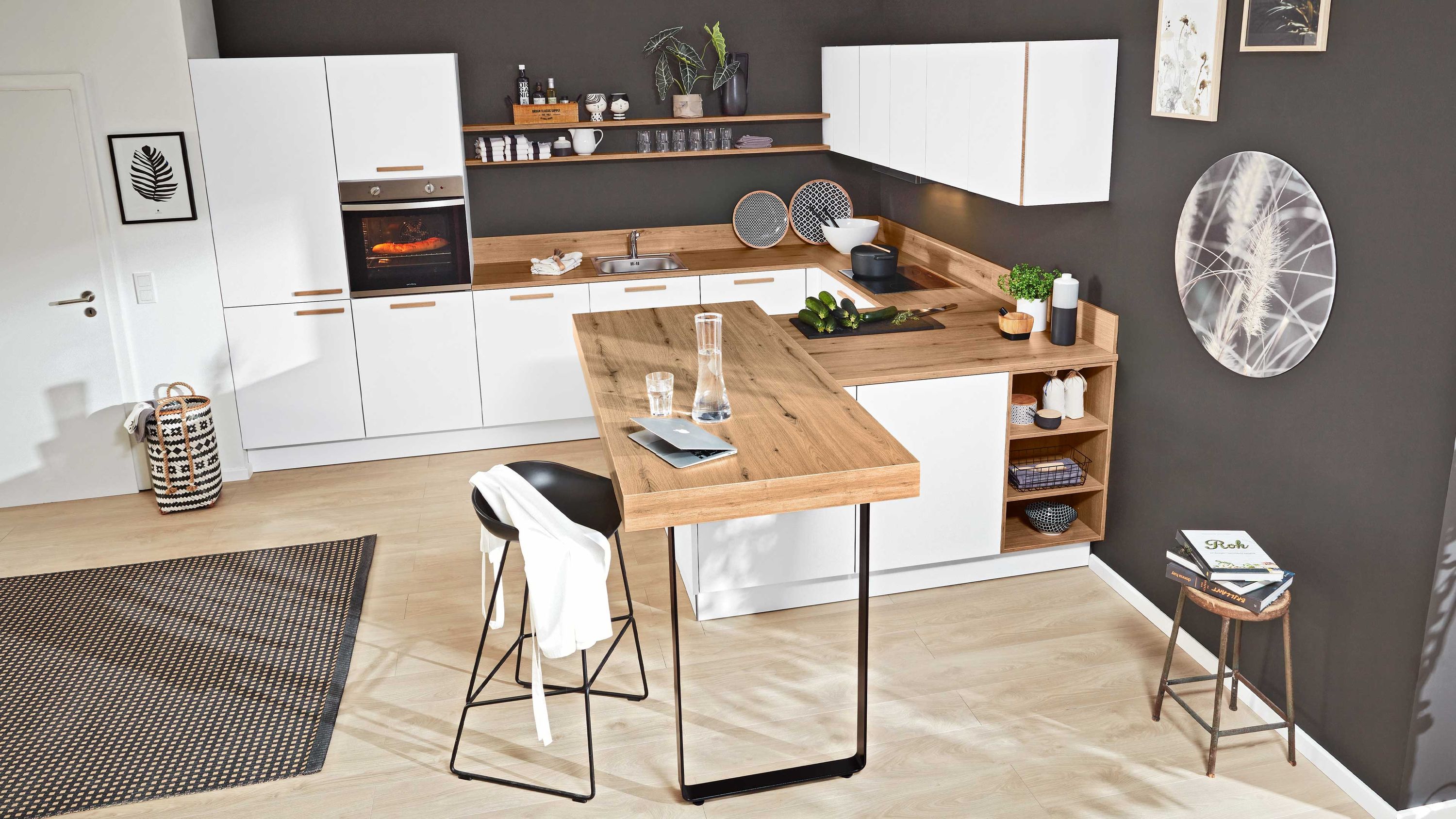 Küche mit weißem Schrank Holzinsel auf Metallgestell schwarzem Hocker dunkler Wand und großer Uhr