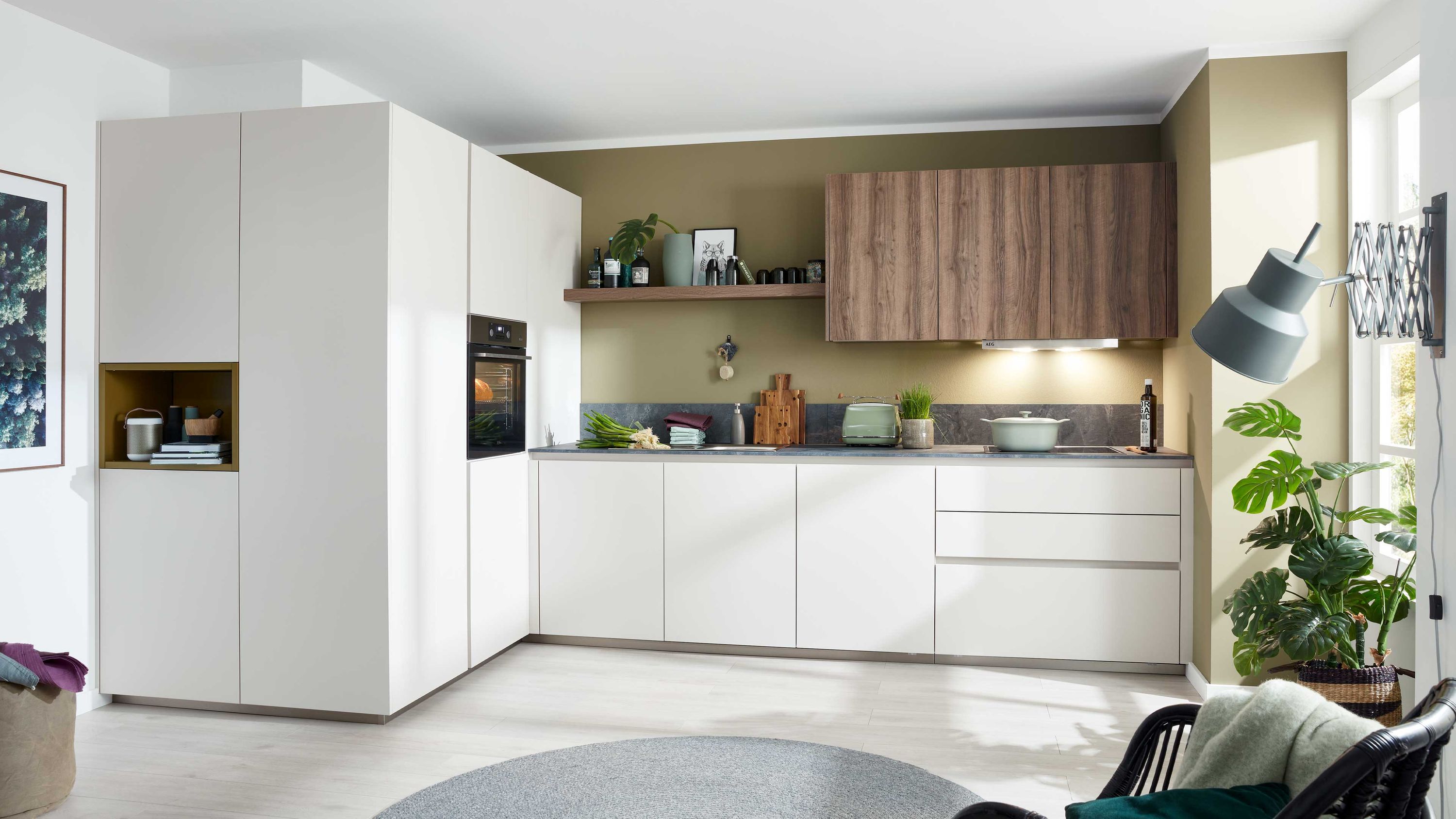 Minimalistische Küche mit Holzakzenten klarer Linienführung und natürlicher Dekoration Küche mit weißen Unterschränken Holzoberschränken Einbauofen Hängelampe Pflanzen helle Wände und Boden